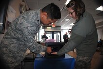 Capt. Chris Ordonez, 319th Medical Group infection preventionist, checks Senior Airman Annabel Pack’s hand for dirt using a black light during a Glo Germ challenge March 3, 2014, at the pharmacy on Grand Forks Air Force Base, N.D. Pack, a 319th Air Base Wing Command Post emergency action controller, participated in the challenge as part of a series of activities put on by the 319th MDG in observance of National Patient Safety Week. (U.S. Air Force photo/Staff Sgt. Luis Loza Gutierrez) 
