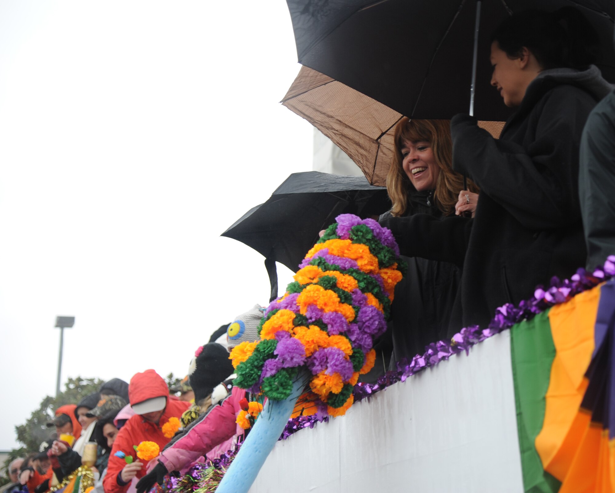The wife of Col. Frank Amodeo, 403rd Wing commander, picks a paper flower during the Gulf Coast Carnival Association Mardi Gras parade in Biloxi, Miss., March 4, 2014. The Keesler Honor Guard and Col. René Romero, 81st Training Wing vice commander, also participated in the festivities. (U.S. Air Force photo by Kemberly Groue)