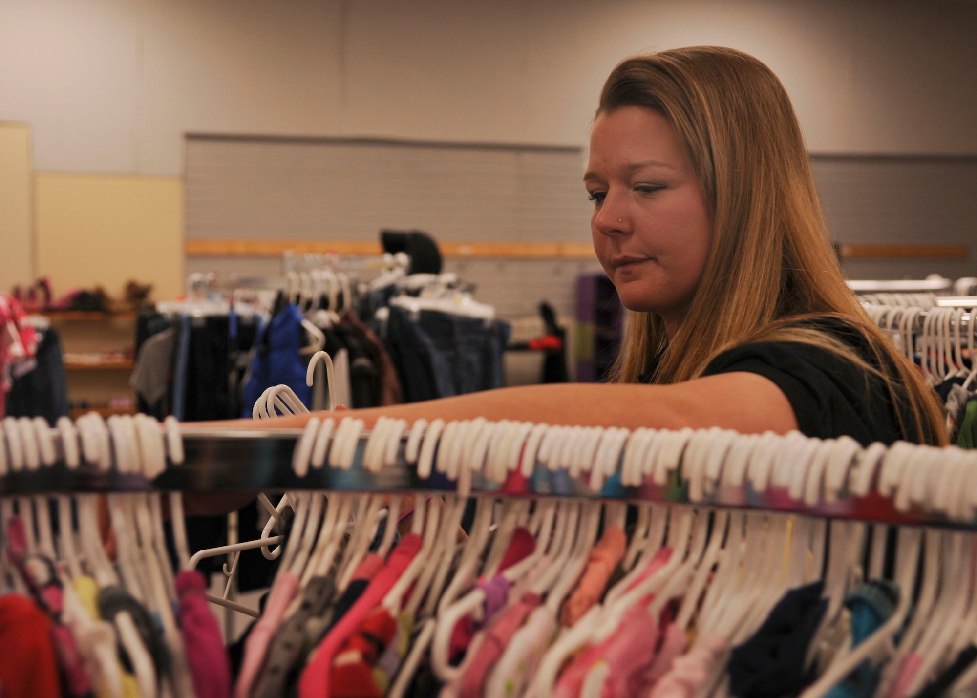 Lindsay Finley, a base Airman’s Attic head volunteer, arranges shirts on a rack March 4, 2014,at Little Rock AFB, Ark. Clothing items are one of the most popular donations to the Airman’s Attic. (U.S. Air Force photo by Airman 1st Class Harry Brexel) 