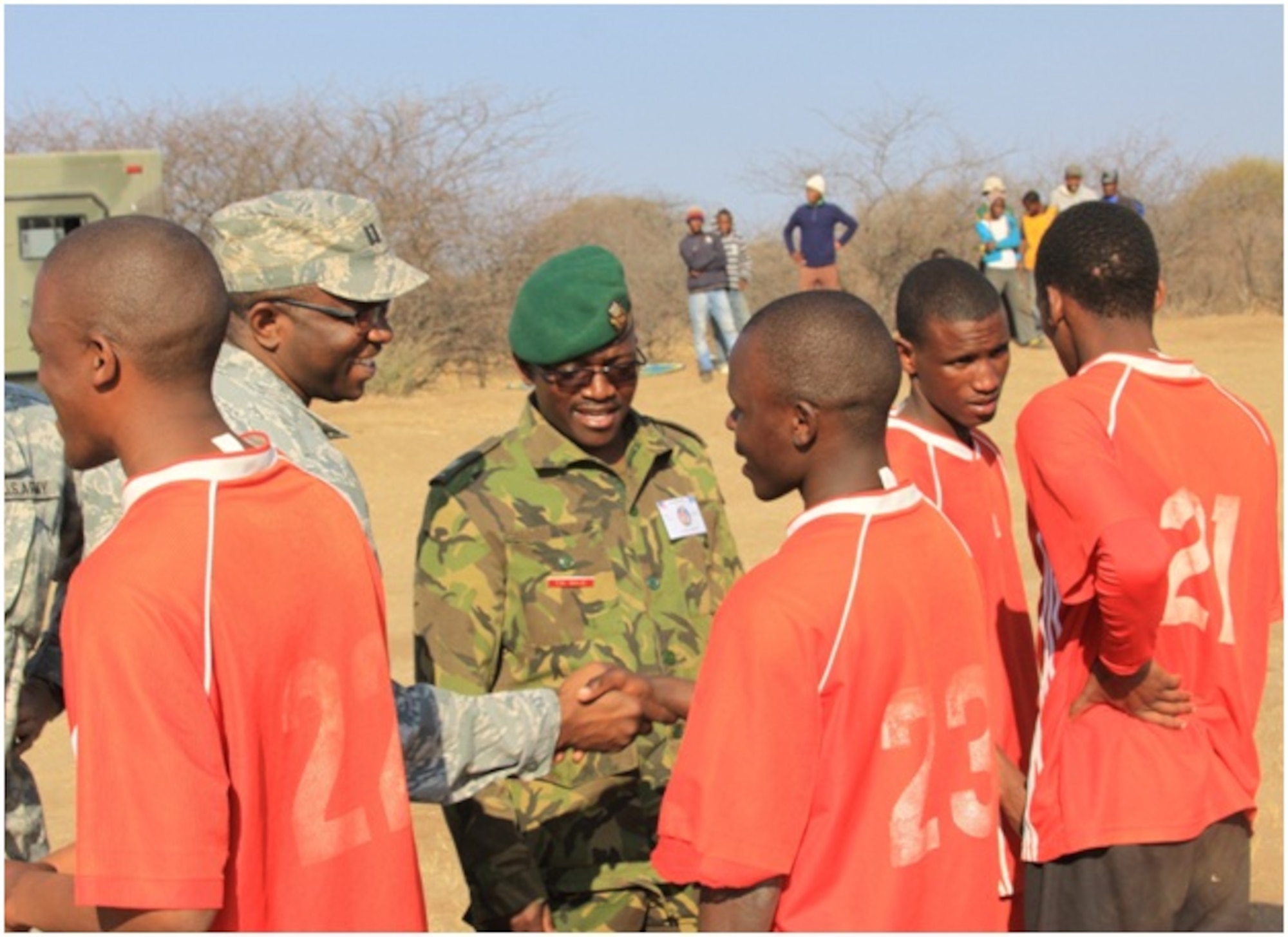 Capt. Francis Obuseh, U.S. Air Forces in Europe - Air Forces Africa international health specialist, and Botswana military doctors shake hands with members of a local soccer team near the village of Monwane, Botswana as part of the activities promoting HIV/AIDS testing, treatment and prevention. (Courtesy photo)