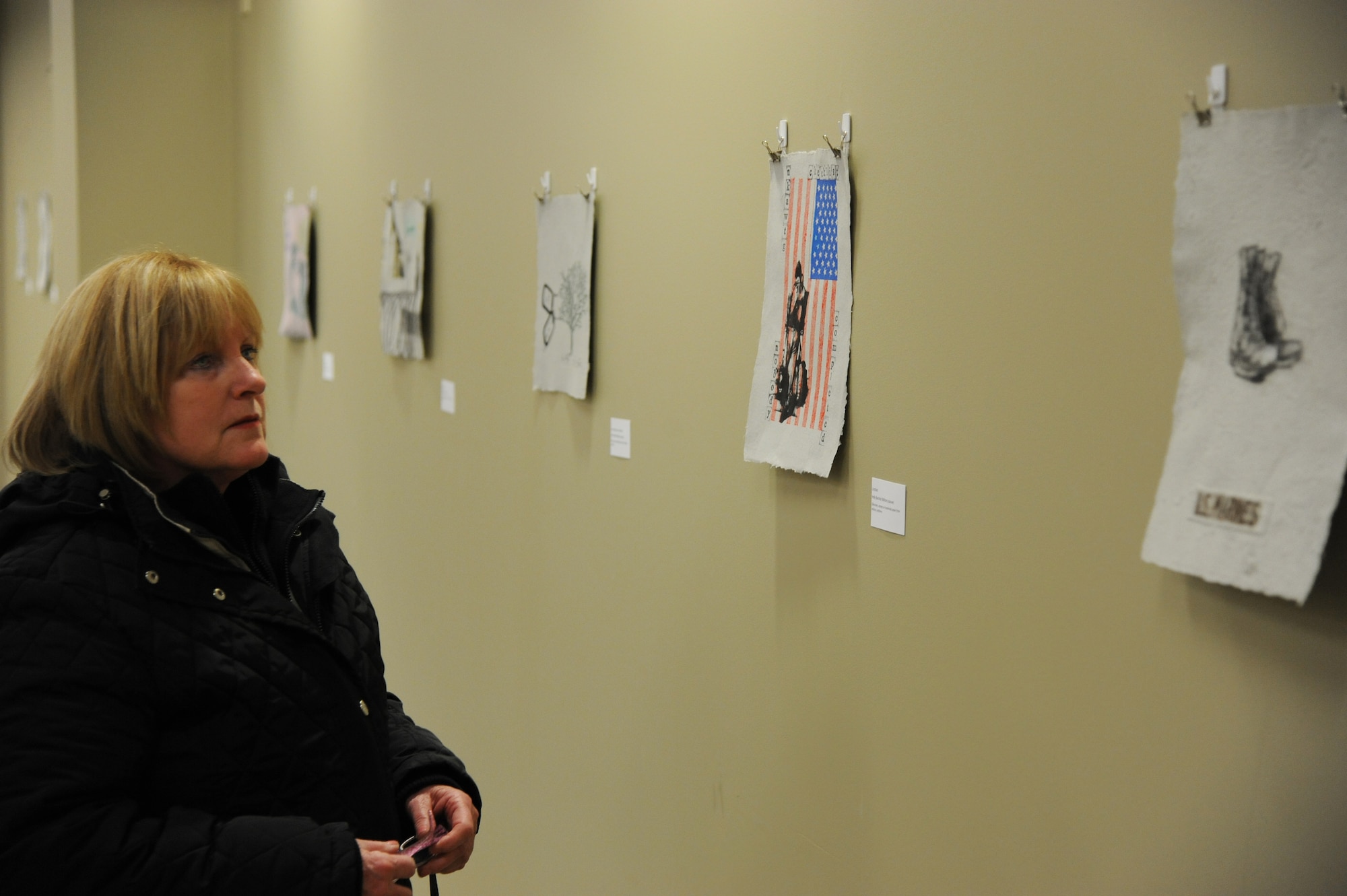 Marie Sherader, retired Air Force master sergeant, views art during the Combat Paper New Jersey exposition Feb. 28, 2014, at Joint Base McGuire-Dix-Lakehurst, N.J. CPNJ is a program intended for veterans to turn military uniforms into paper to make expressive artwork, showing the military experience they chose to communicate. (U.S. Air Force photo by Airman 1st Class Sean M. Crowe/Released)