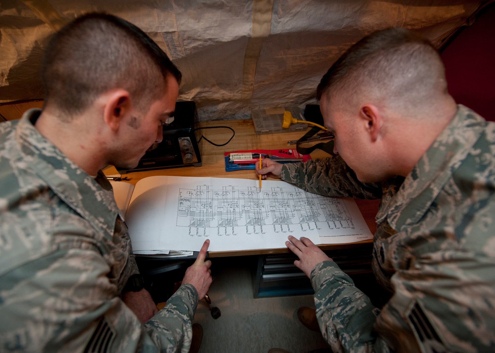 Staff Sgt. Aaron Driver and Senior Airman Justin Elder, both ground radar systems technician assigned to the 727th Expeditionary Air Control Squadron, review technical orders at an undisclosed location in Southwest Asia, March 5, 2014. Driver and Elder are both deployed here from Hunter Army Airfield in Savannah, Ga. (U.S. Air Force photo by Staff Sgt. Michael Means/Released)