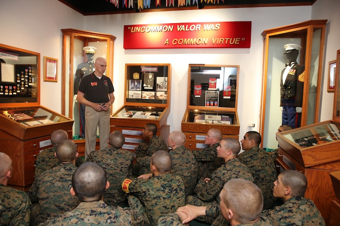 Retired Capt. Joe Larkin, museum docent, teaches Marines about Marine Corps uniforms during a Command Museum visit aboard the depot, Feb. 19. Since 1775, the Marine Corps has left a trail of history and traditions ranging from different battles to the uniforms worn today.