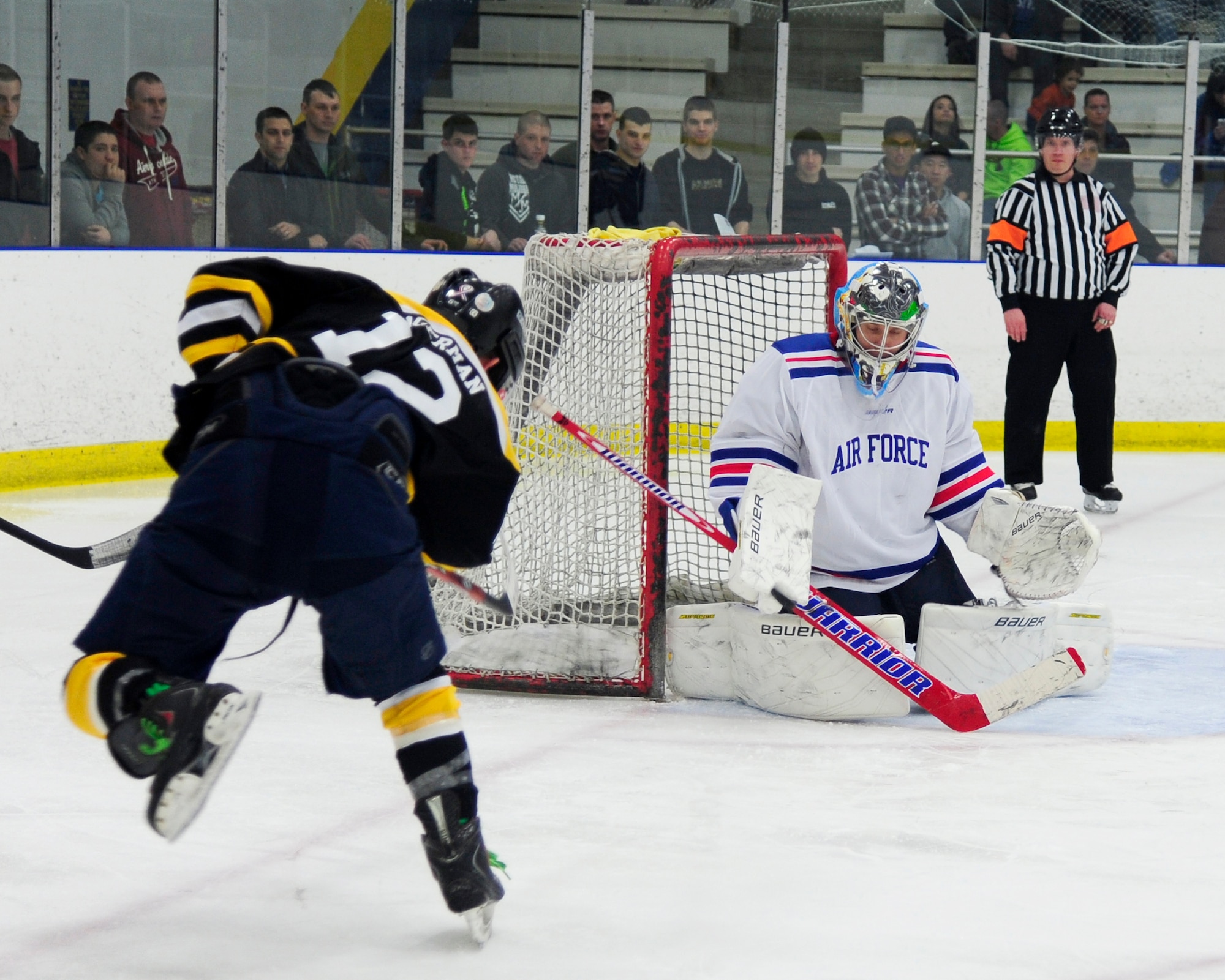 Charlie Siegfred, Eielson goalie, blocks a shot from Nicholas Hagermann, Army defenseman, during the final period of the Commanders’ Cup hockey game at the University of Alaska Fairbanks Patty Center, Feb. 28, 2014, Fairbanks, Alaska. Eielson Airmen and Ft. Wainwright Soldiers filled the seats and lined the boards for the annual faceoff, filling the arena to capacity. (U.S. Air Force photo/Tech. Sgt. Tim Jenkins)