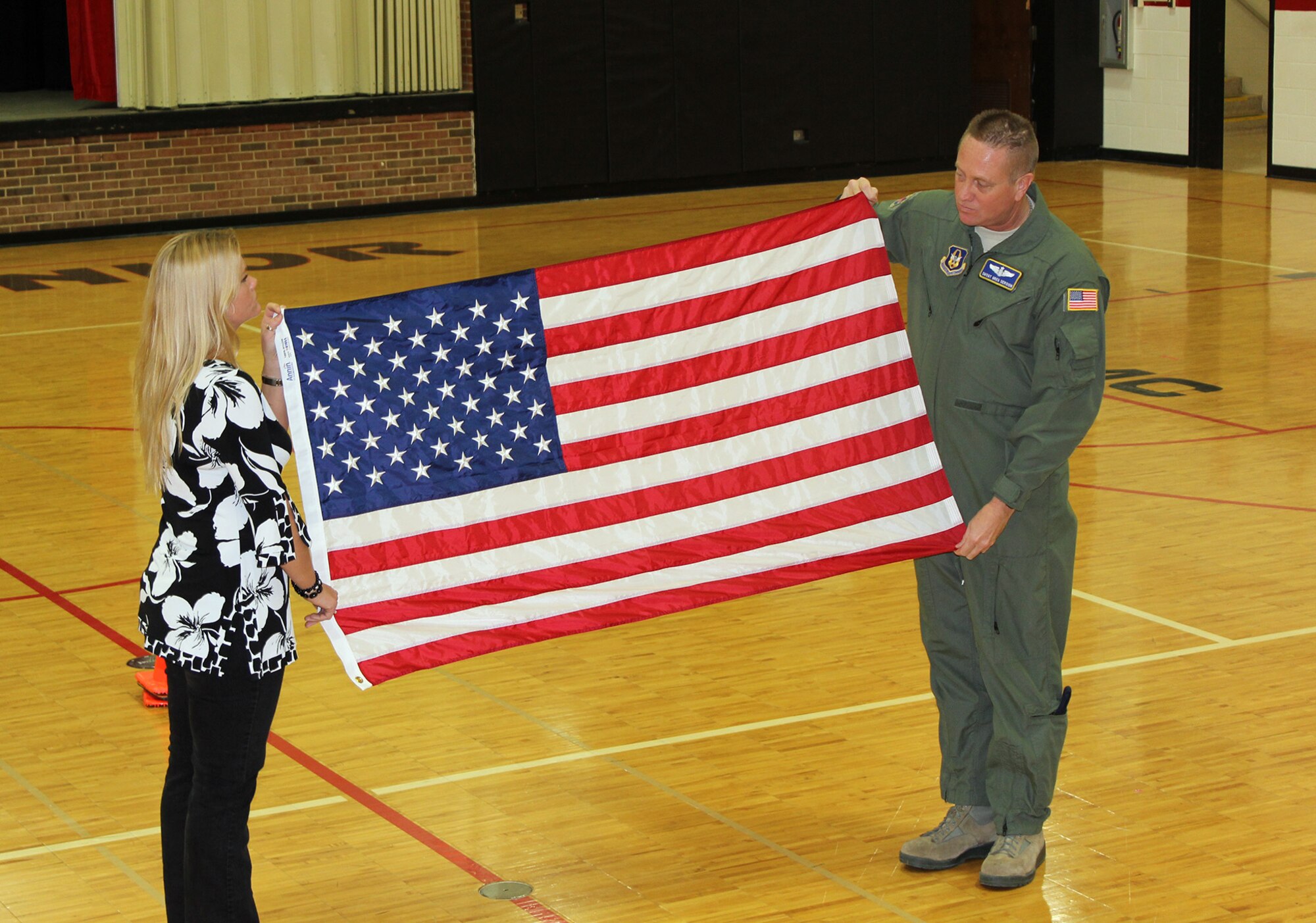 WRIGHT-PATTERSON AIR FORCE BASE, Ohio - Senior Master Sgt. Gregory Sersion, 445th Aeromedical Evacuation Squadron, and his wife, Jody, perform a flag folding presentation using the flag he brought back from his deployment and was presented to Hopewell Junior School, West Chester, Ohio, Feb. 19, 2014. The flag was a small token of his appreciation for the overwhelming support the students gave him while deployed. (Courtesy photo)