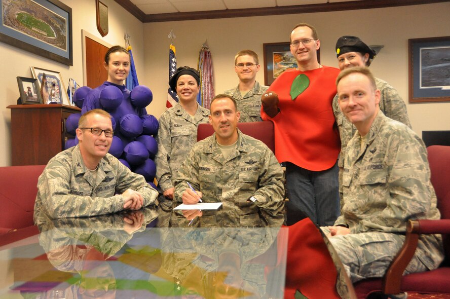 Col. Matthew Burger, seated left, 349th Air Mobility Wing commander; Col. Leonard Kosinski, seated center, 60th Air Mobility Wing vice commander; and Col. Bradford Johnson, seated right, 571st Contingency Response Group commander; sign the National Nutrition Month proclamation March 5. (U.S. Air Force photo/Senior Airman Madelyn Brown)