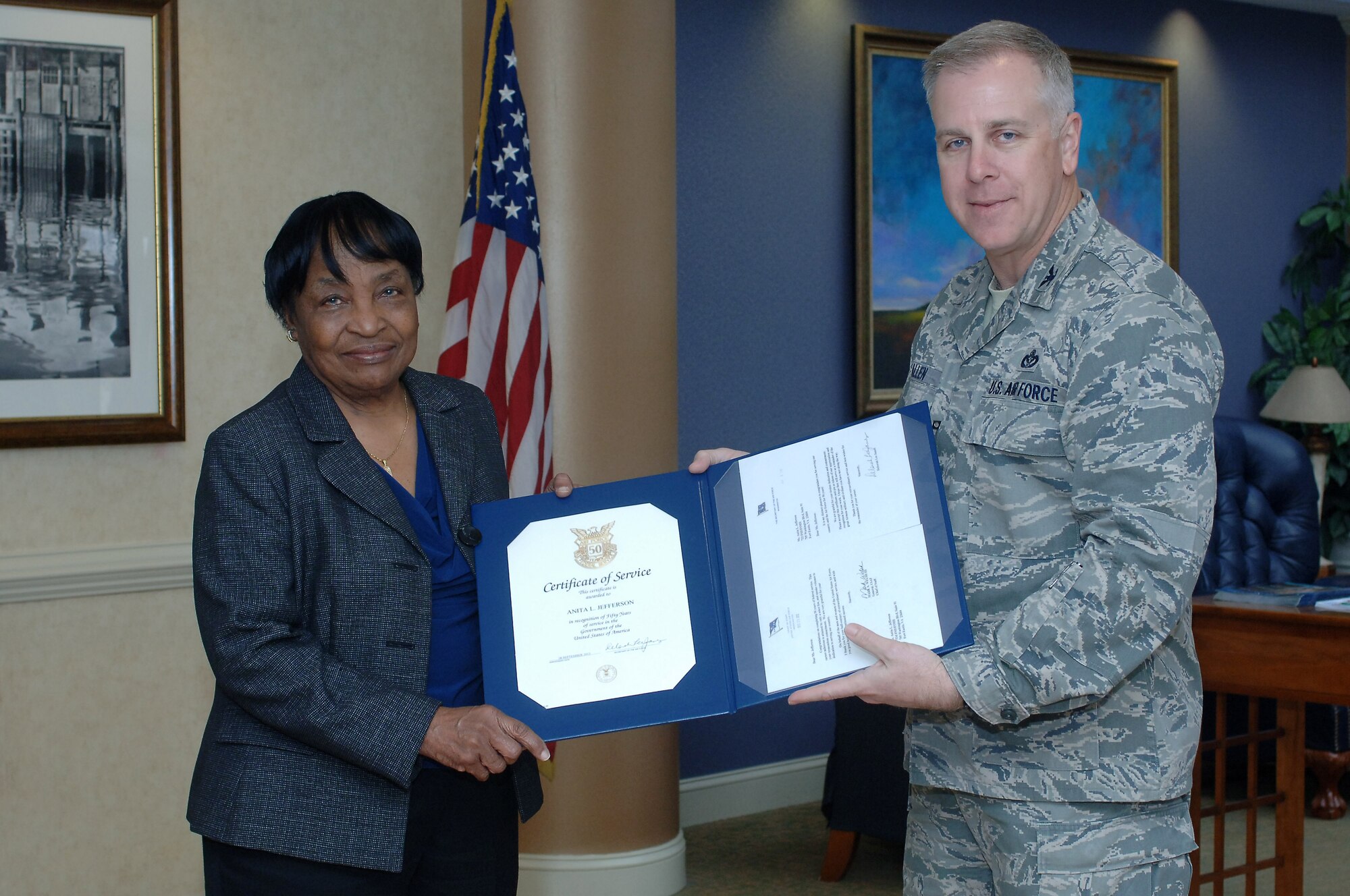 U.S. Air Force Col. John J. Allen Jr., Joint Base Langley-Eustis installation commander, presents a Certificate of Service on behalf of the Secretary of the Air Force to Anita Jefferson, 733rd Force Support Division lodging custodial supervisor, during a visit to Fort Eustis, Va., Mar. 6, 2014. Jefferson celebrated her 50th year as a government employee in September 2013 and has worked her entire career at Fort Eustis' post lodging. (U.S. Air Force photo by Senior Airman Teresa J.C. Aber/Released)