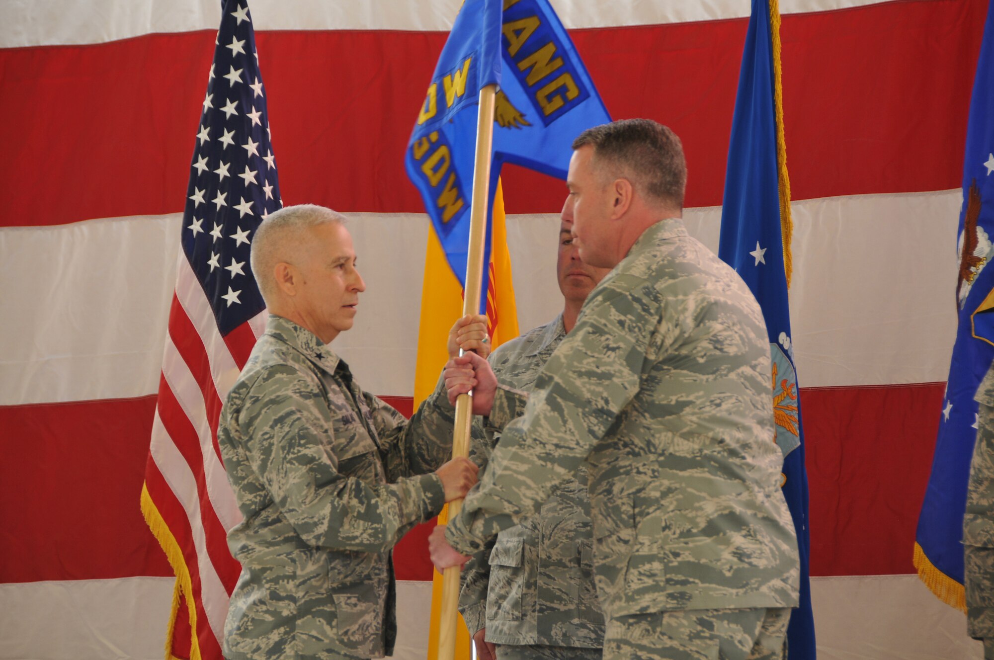 Brig. Gen. Andrew Salas, New Mexico National Guard Adjutant General, left, passes the 150th Special Operations Wing guidon to Col. Clark Highstrete, 150th SOW commander, right, while Chief Master Sgt. John Williams, state command chief, center, waits to take possession of the unit flag. (Photo by Master Sgt. Paula Aragon)
