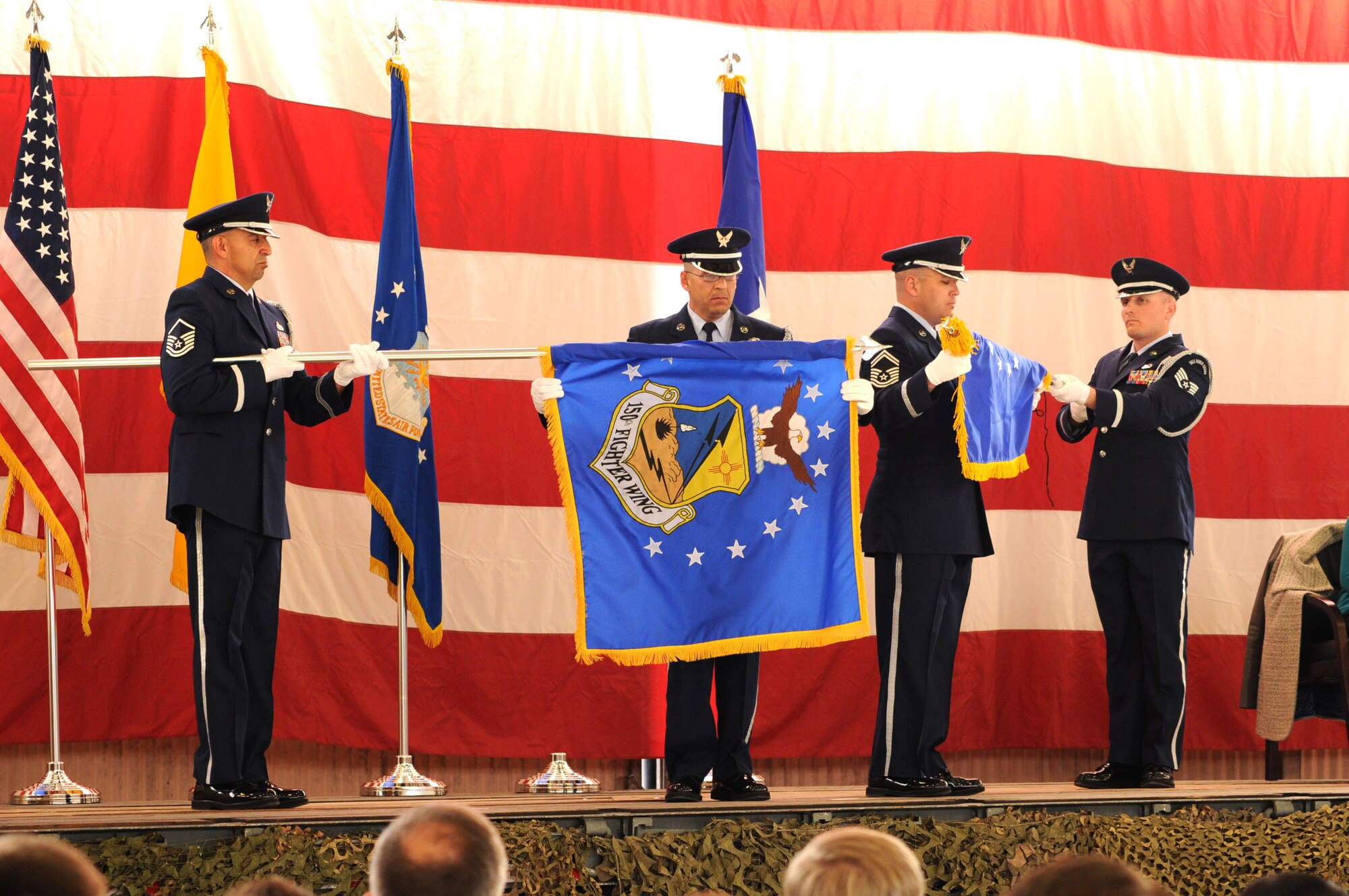 Master Sgt. Guadalupe Castaneda, left, and Senior Master Sgt. Rubel Tafoya, second from left, furl the 150th Fighter Wing guidon, while Senior Master Sgt. Keith Gum, second from right, and Staff Sgt. Justin Gabaldon, right, unfurl the 150th Special Operations Wing guidon during the unit’s March 1 redesignation ceremony at Kirtland AFB. (Photo by Tech. Sgt. Roberto Bilbao)
