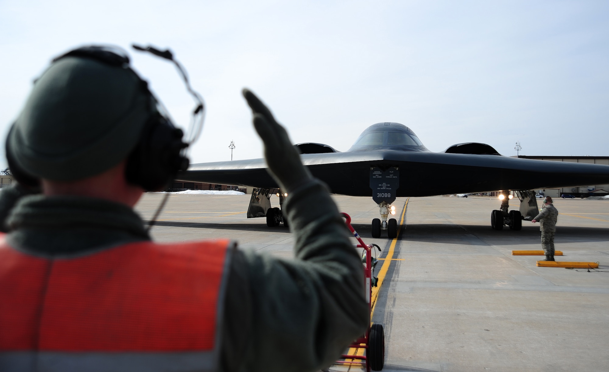 Senior Airman Joshua Thompson and Airman 1st Class James Fulton, both 509th Aircraft Maintenance Squadron crew chiefs, marshal a B-2 during an engine-run and crew-change at Whiteman Air Force Base, Mo., Feb. 24, 2014.  The engine-run and crew-change allows pilots to swap out personnel during shift changes and enable the mission to continue on the same aircraft. (U.S. Air Force photo by Staff Sgt. Nick Wilson/Released)