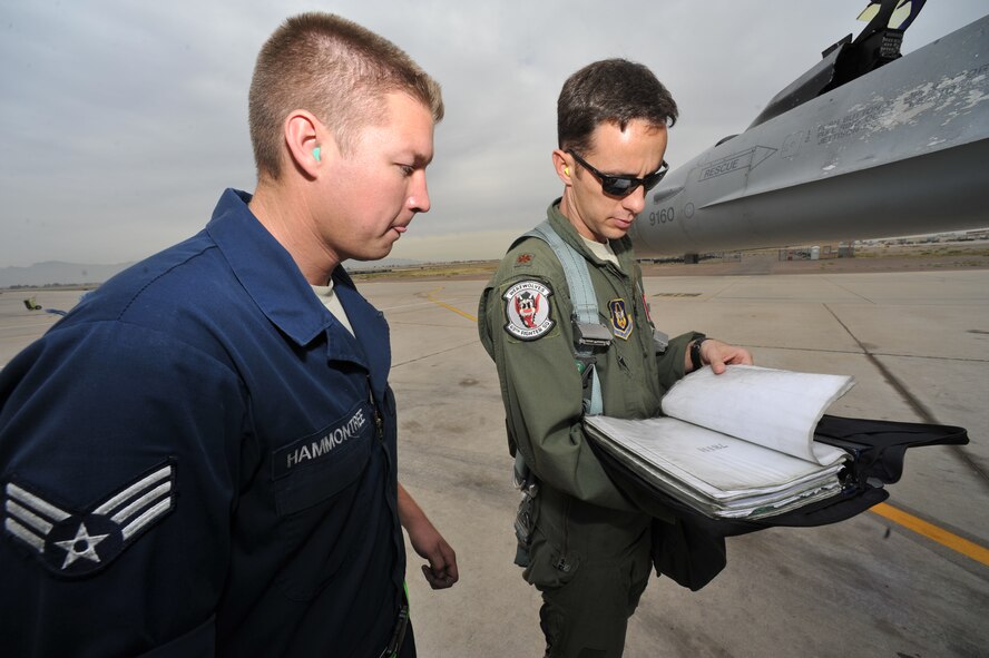 Senior Airman Jesse Hammontree, 756th Aircraft Maintenance Squadron crew chief, and Maj. Justin Robinson, 69th Fighter Squadron instructor pilot, review the maintenance records of the F-16 Fighting Falcon Robinson is about to fly. (U.S. Air Force photo/Senior Airman Jason Colbert)