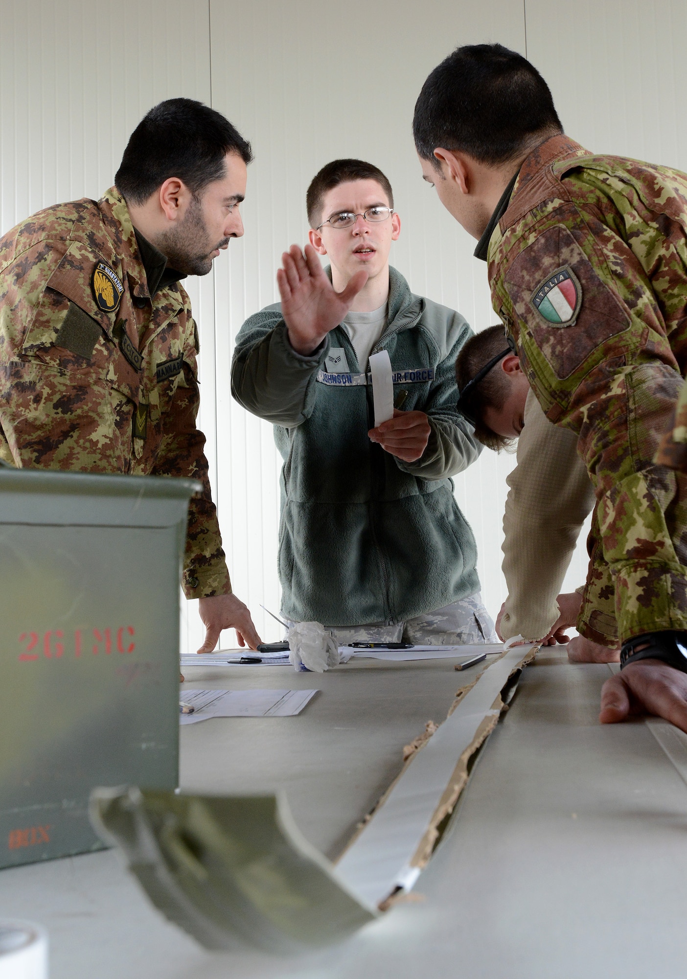 Senior Airman Jacob Johnson , center, 31st Civil Engineer Squadron explosive ordnance disposal technician, demonstrates how to properly place breaching charges on a fixed surface Feb. 26, 2014, at Aviano Air Base, Italy, during a two-day training course between the U.S. Air Force and Italian army. The first-ever joint endeavor allowed the service members from both nations the opportunity to share best practices involving EOD operations. (U.S. Air Force photo/Staff Sgt. R.J. Biermann)