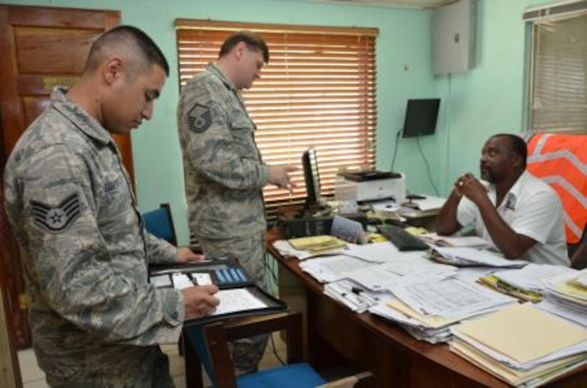 Staff Sgt. Eliseo Guerrero, New Horizons lead logistical planner, and Master Sgt. Scott Stambaugh, New Horizons Belize transportation manager, talk with Kenrick Richards, Port of Belize cargo operations manager, about a large military sea shipment scheduled to arrive at the port on March 8. Once the shipment arrives, the vehicles and shipping containers will be transported to various New Horizons exercise sites throughout the country. (U.S. Air Force photo by Master Sgt. Kelly Ogden/Released)


