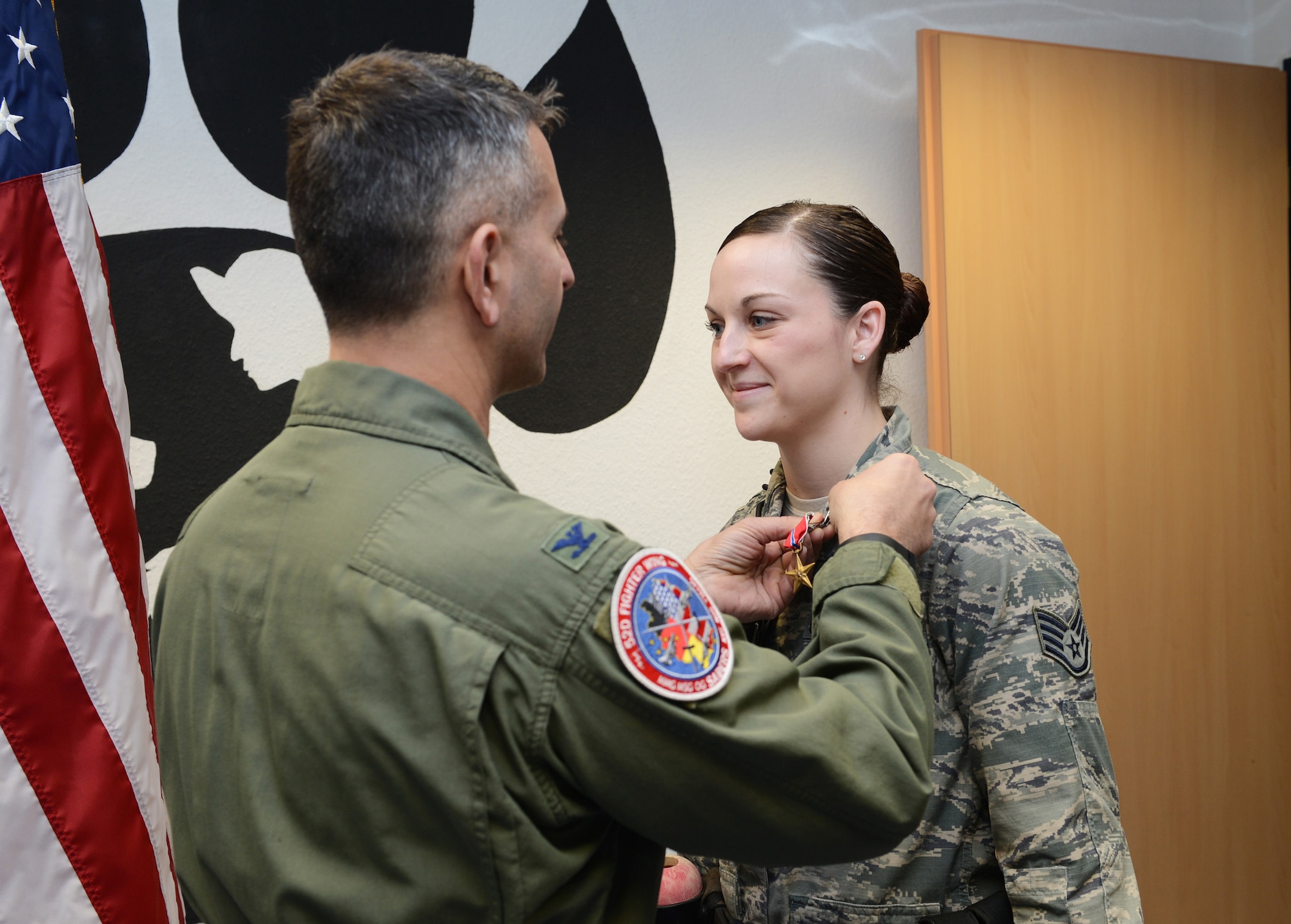 U.S. Air Force Col. David Julazadeh, 52nd Fighter Wing commander, presents a Bronze Star to Staff Sgt. Shannon Hennessy, 52nd Security Forces Squadron military working dog handler, at the MWD kennel on Spangdahlem Air Base, Germany, Feb. 27, 2014. Hennessy and her MWD "Katya" recently returned from a six-month deployment with the Combined Joint Special Operations Task Force in Afghanistan. (U.S. Air Force photo by Staff Sgt. Chad Warren/released)