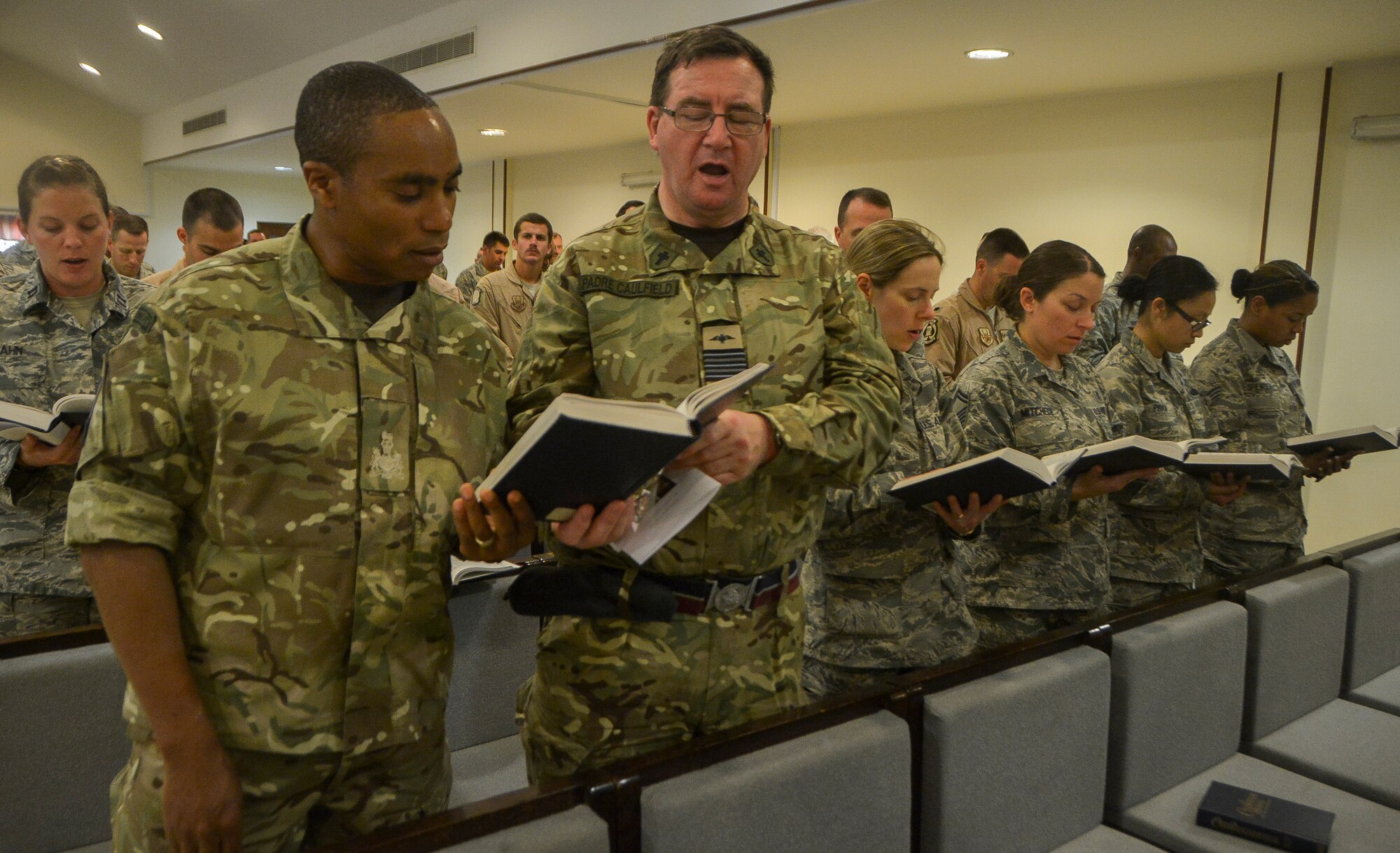 Airmen and coalition partners sing a hymn during a memorial service for Master Sgt. David Poirier at Al Udeid Air Base, Qatar, Mar. 3, 2014, to honor the fallen hero. Poirier died on Feb. 28, 2014 in a non-combat-related incident while deployed supporting Operation Enduring Freedom. Porier was a member of the New Hampshire Air National Guard’s 157th Operations Support Squadron at Pease Air National Guard Base, N.H., and was a postmaster while not on duty. Poirier served in the military for more than 22 years. (U.S. Air Force photo/Senior Airman Jared Trimarchi) 