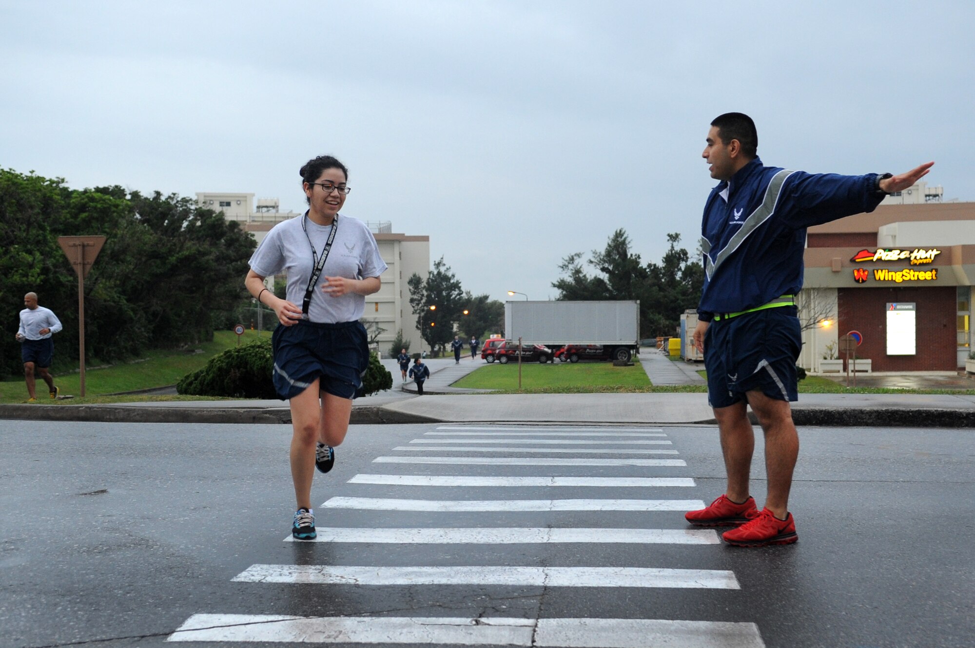 U.S. Air Force Staff Sgt.  Alejandro Juarez, 18th Dental Squadron dental assistant, directs a member from the 18th Medical Group during a 5k on Kadena Air Base, Japan, March 7, 2014. Team Kadena members participated in the run in support of National Patient Safety Awareness Week. Each year health care organizations from around the world take part in the event by creating awareness in their community and among their staff. (U.S. Air Force photo by Staff Sgt. Amber E. N. Jacobs)