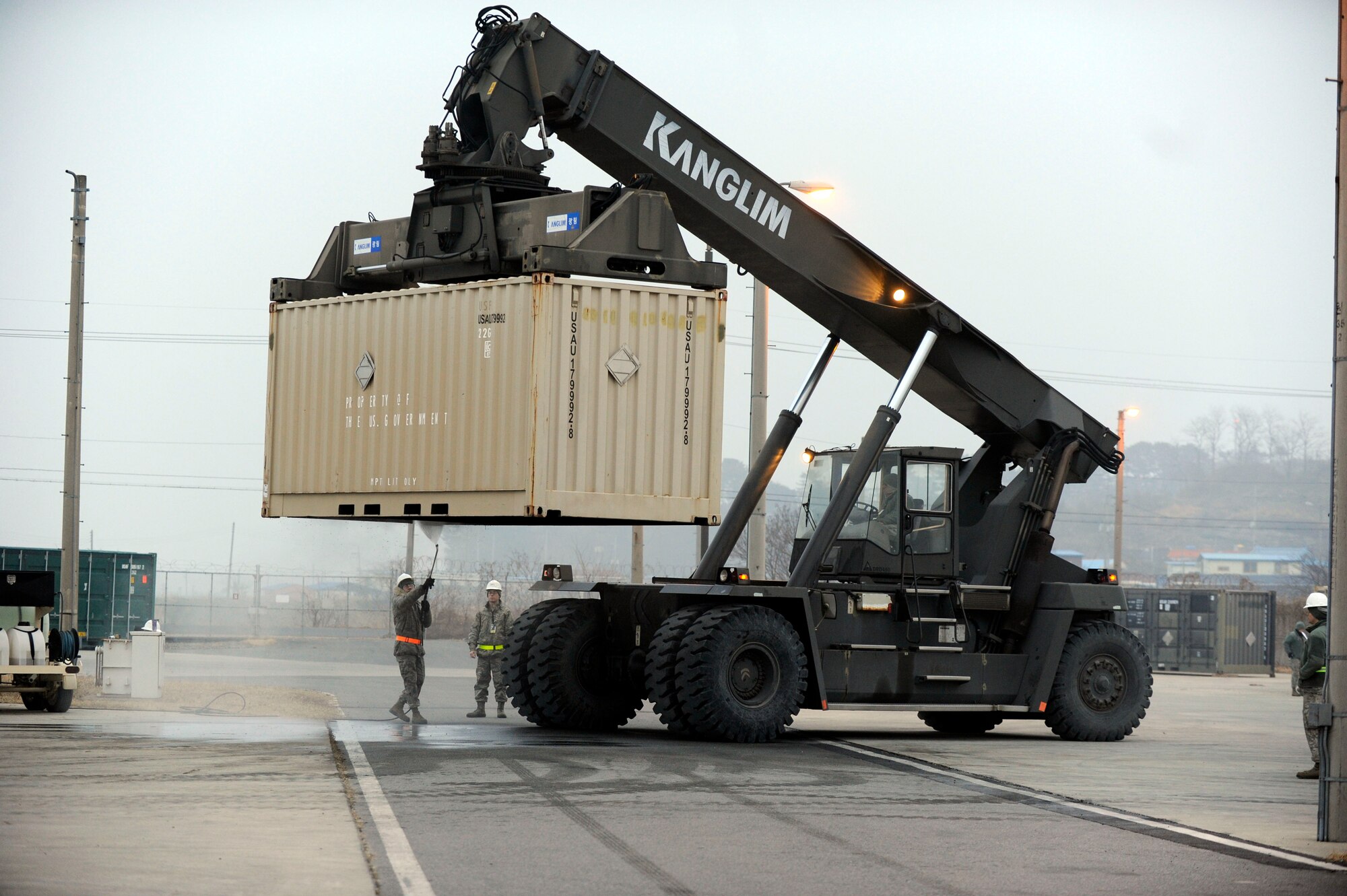 Airmen from both the 8th Maintenance Squadron and the 8th Logistics Readiness Squadron work to together to prepare crates of munitions to be loaded onto tractor-trailers during a peninsula-wide munitions realignment at Kunsan Air Base, Republic of Korea, Feb. 26, 2014. Spraying the crates down before loading was done to prevent the introduction of foreign agricultural materials into other parts of the world. The realignment efforts allow the 8th Fighter Wing to better meet operational requirements by decreasing periodic inspection requirements, munition container repairs and re-warehousing. (U.S. Air Force photo by Staff Sgt. Jessica Haas/Released)