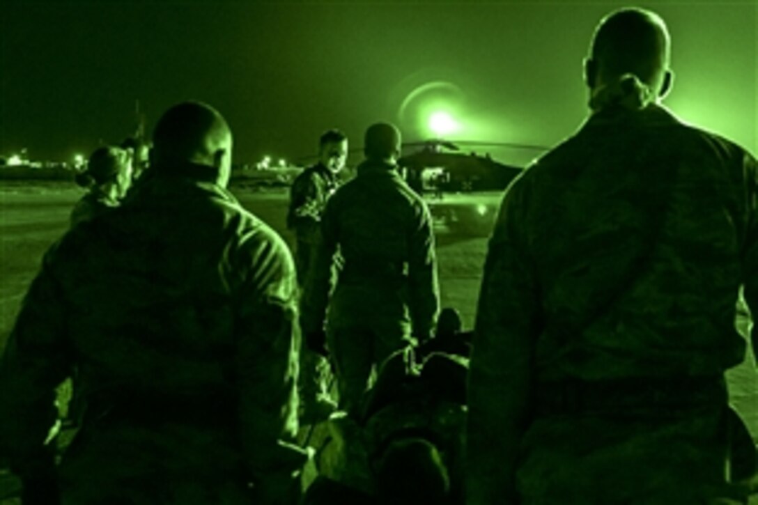 As seen through a night-vision device, Sgt. 1st Class Michael Ball leads U.S. airmen carrying a mock casualty into his waiting UH-60 Black Hawk medical evacuation helicopter during hot load training in southwest Asia, Feb. 28, 2014. Ball is a flight medic assigned to the Kentucky Army National Guard's Company C, 2nd Battalion, 238th Air Ambulance, 42nd Combat Aviation Brigade. 