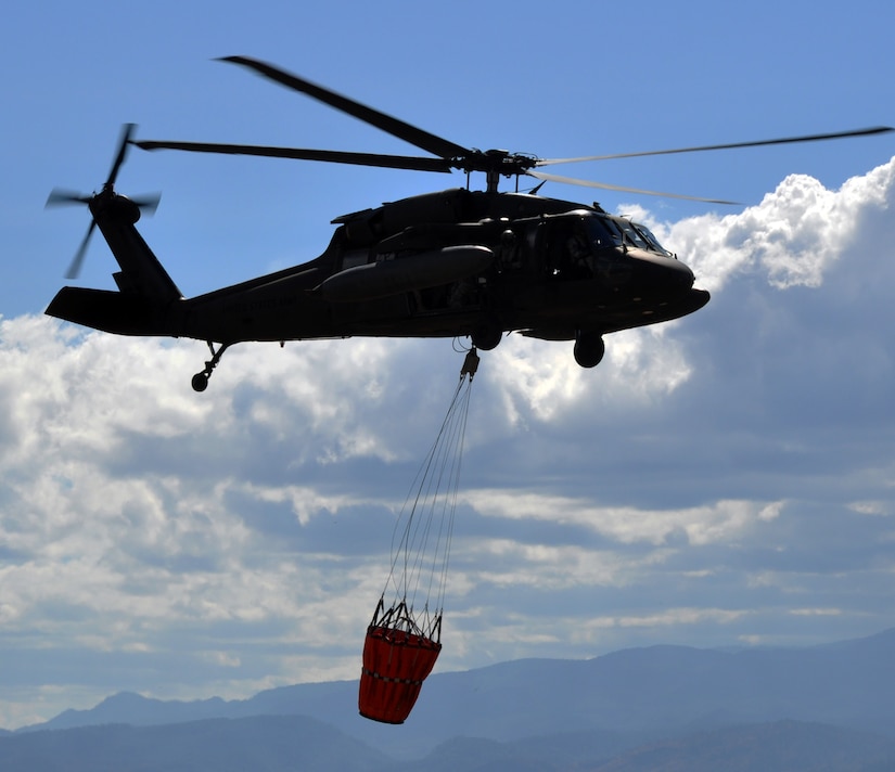 A UH-60 Blackhawk helicopter assigned to Joint Task Force-Bravo's 1-228th Aviation Regiment carries a Bambi bucket en route to an aerial firefighting mission in Honduras.  The 1-228th utilized the Bambi buckets to battle a fire that was threatening villages near Soto Cano Air Base, Honduras on the evening of March 4, 2014.  Two Blackhawks flew under night vision goggles and dropped more than 10,000 gallons of water over a four-hour span to extinguish the blaze.  (U.S. Air Force photo by Capt. Zach Anderson) 