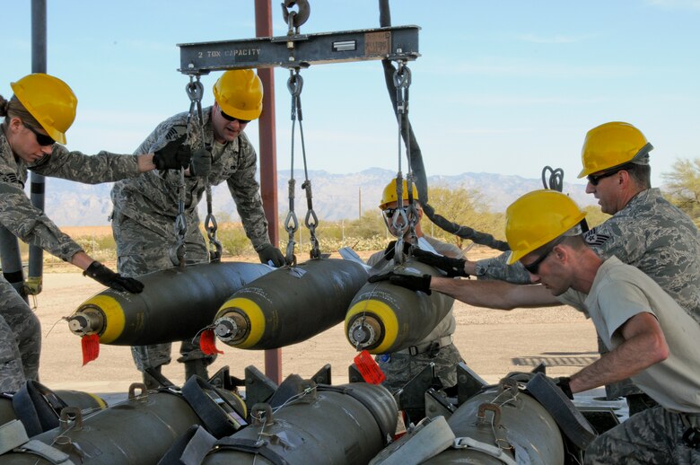A picture of U.S. Air Force aircraft armament systems specialists from the 177th Fighter Wing transporting Mark 82s onto a trailer on the munitions assembly conveyor pad.