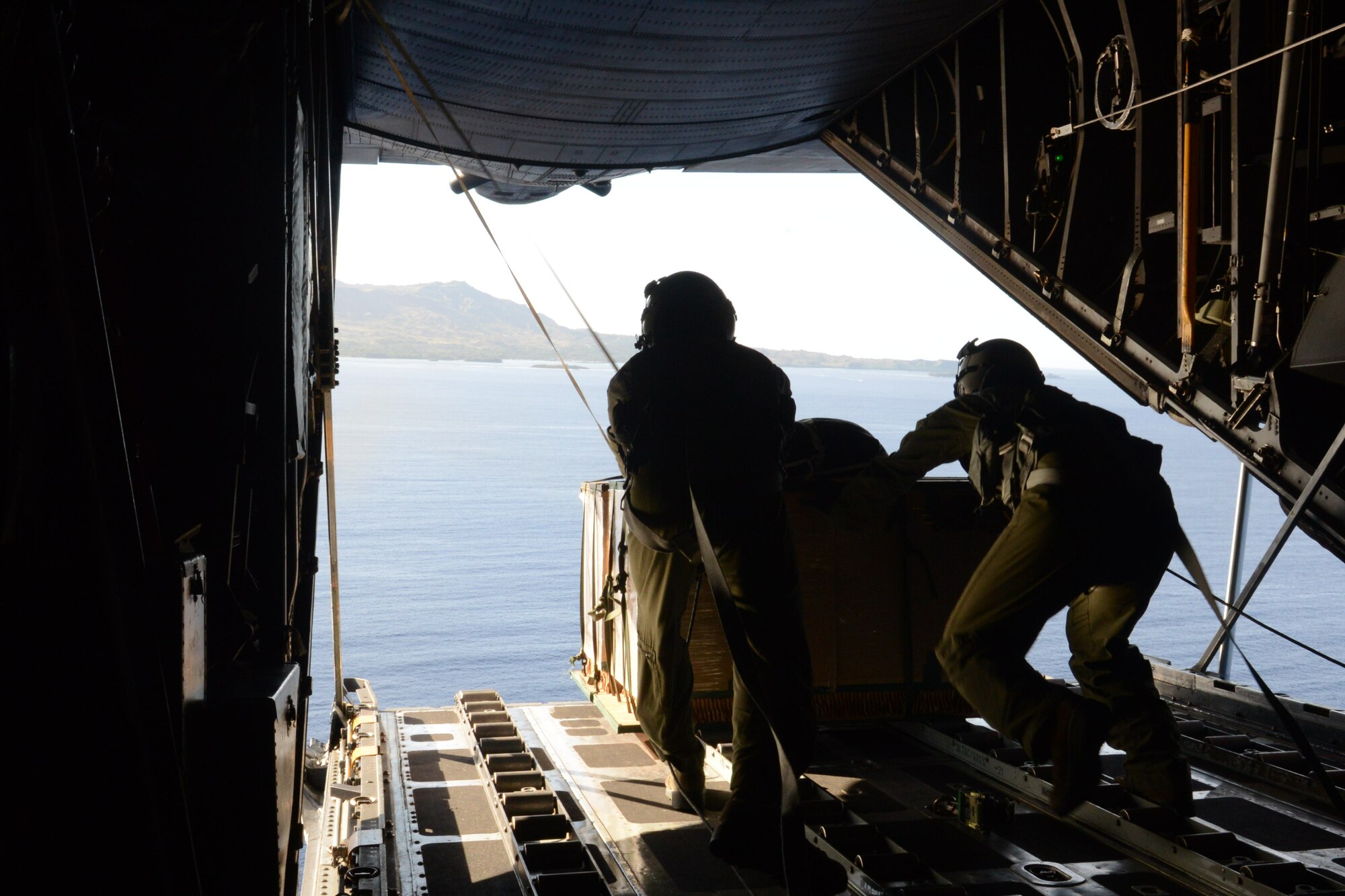 Airman 1st Class Andrew Fox and Staff Sgt. Ralph Oliver, both 36th Airlift Squadron loadmasters, push an airdrop bundle out of a C-130 Hercules during humanitarian assistance and disaster relief training Feb. 20, 2014, off the coast of Orote Point, Naval Base Guam during Exercise Cope North 2014. Cope North is a multilateral aerial and humanitarian assistance and disaster relief exercise, held annually, designed to increase the combat readiness and interoperability of the U.S. Air Force, U.S. Navy, Japan Air Self-Defense Force, Royal Australian Air Force and Republic of Korea Air Forces. (U.S. Air Force photo by Airman 1st Class Emily A. Bradley/Released)