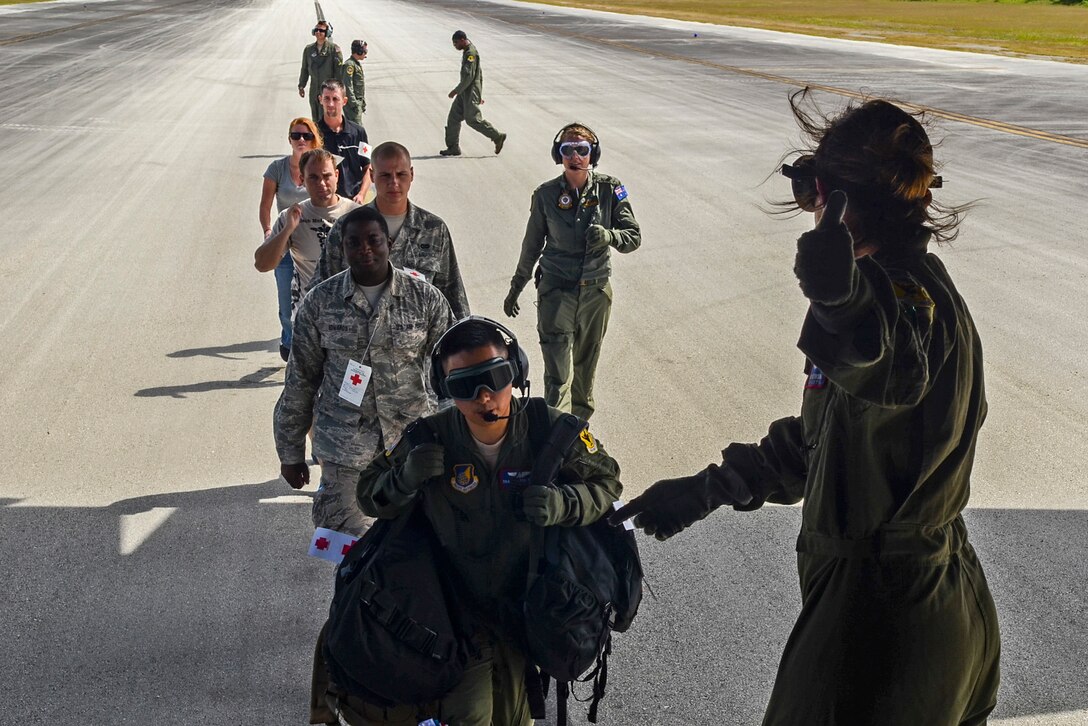 U.S. Air Force Capt. Amy Jacobson, 18th Aeromedical Evacuation Squadron flight nurse from Kadena Air Base, Japan, guides American and Australian aeromedical evacuation crewmembers and simulated patients into a C-130 Hercules at the flightline on Tinian, Commonwealth of the Northern Mariana Islands, Feb. 18, 2014, during a patient transport exercise as part of Exercise Cope North 2014. Australian and U.S. medical crews worked together as one team to move simulated patients from a site on Tinian onto a C-130 Hercules and provided medical care for the duration of the flight back to Andersen Air Force Base, Guam. (U.S. Air  Force photo by Senior Airman Marianique Santos/Released)