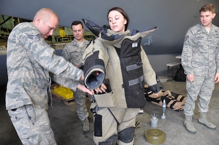 Senior Airman Jeremy Weant, Explosive Ordnance Disposal specialist with the 433rd Civil Engineering Squadron, attaches a battery pack to a bomb disposal suit worn by Angelica White, an employer from United Services Automobile Association. Senior Airman Ryan Beckmann and Tech Sgt. Cody Cochran, also EOD specialists, then challenged White, who volunteered to try on the suit, to move in the 85-pound suit. (U.S. Air Force photo by Tech Sgt. Carlos Trevino)