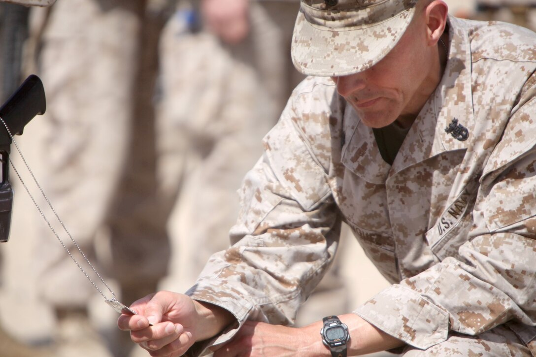 Master Chief Petty Officer Frank Dominguez, command master chief of Regional Command (Southwest), pays his respect to the battlefield cross of Lance Cpl. Caleb L. Erickson aboard Camp Leatherneck, Afghanistan, March 7. Erickson, of Waseca, Minn., a motor transportation mechanic stationed out of Camp Lejeune, N.C., died while conducting combat operations in Helmand province, Afghanistan, Feb. 28, 2014.