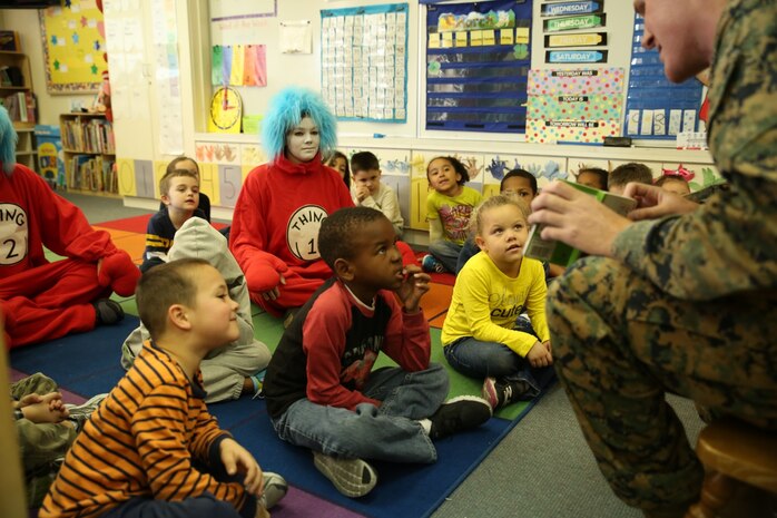 Kindergarten students listen to Lance Cpl. Tommy Fears, flight equipment technician with Marine Aviation Logistics Squadron 12, read “Mr. Brown Can Moo! Can You?” by Dr. Seuss at Matthew C. Perry Elementary School aboard Marine Corps Air Station Iwakuni, Japan, for Read Across Department of Defense Education Activity Day March 3, 2014. Thing 1 and Thing 2, characters from the popular children’s book “Cat in the Hat” by Theodor Seuss Geisel, better known as Dr. Seuss, accompanied Fears for the event.