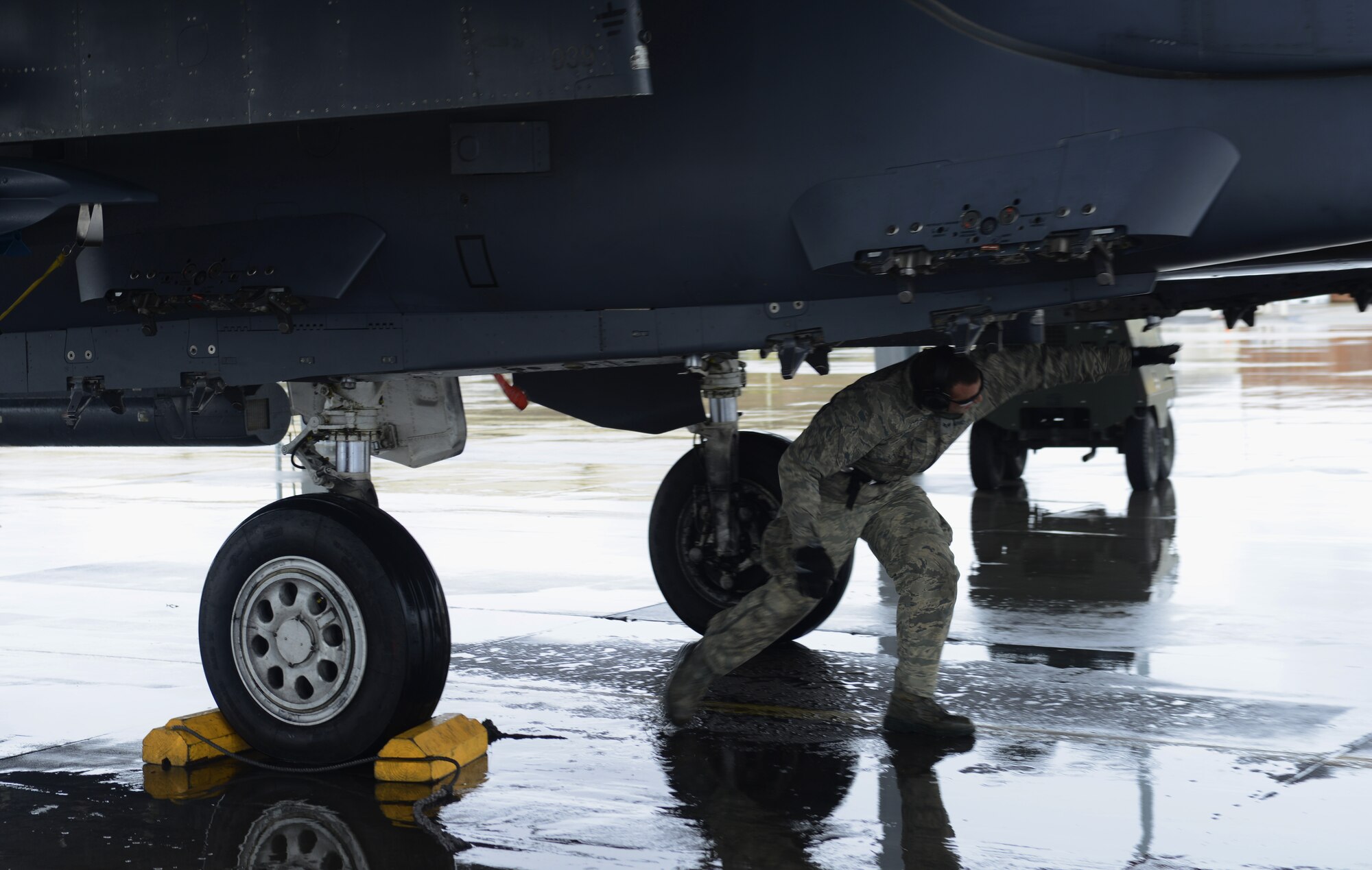 Senior Airman Ben Failer, 366th Aircraft Maintenance Squadron aircraft armament systems technician, checks the underside of an F-15E Strike Eagle during a recovery March 10, 2014, at Mountain Home Air Force Base, Idaho. Despite the wet and soggy conditions, Airmen ensured aircraft were able to fly and support the combat exercise Gunighter Flag. Gunfighter Flag will continue thru March 14 and is an excellent opportunity to prepare multiple joint and coalition terminal attack controller teams for upcoming deployments as well as provide proficiency training for air and ground crews. (U.S. Air Force photo by Senior Airman Ben Sutton/Released)