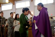 Chaplain (Capt.) Ruben Covos, draws the a cross on the foreheads of Airmen and family members attending Ash Wednesday service March 5, 2014, at the Sunflower Chapel on Grand Forks Air Force Base, N.D. Father Ruben is one of three active-duty  Air Force chaplains serving on the base, and is a Catholic priest assigned to the Archdiocese for Military Services, United States of America. (U.S. Air Force photo/Staff Sgt. Luis Loza Gutierrez)