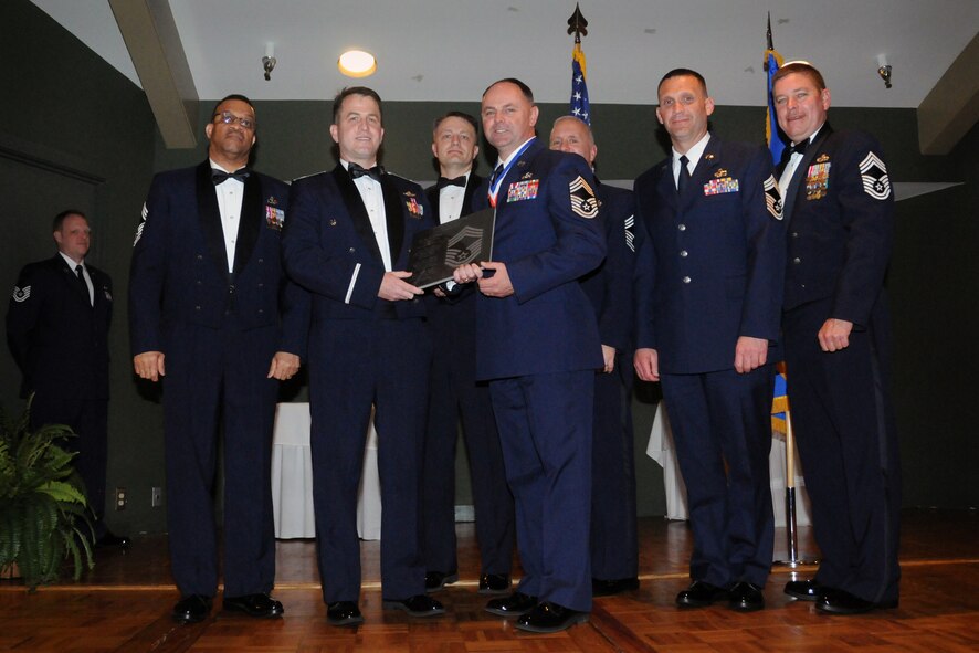 Chief Master Sgt. Gary Smith, 567th Red Horse manager, recieves a promotion plaque from Col. Craig Shenkenberg during an NCO induction ceremony held at Walnut Creek Country Club, March 10. Smith and Shenkenberg were joined on-stage by all chiefs in attendance. (U.S. Air Force photo by Staff Sgt. Alan Abernethy, 916th ARW/PA) 