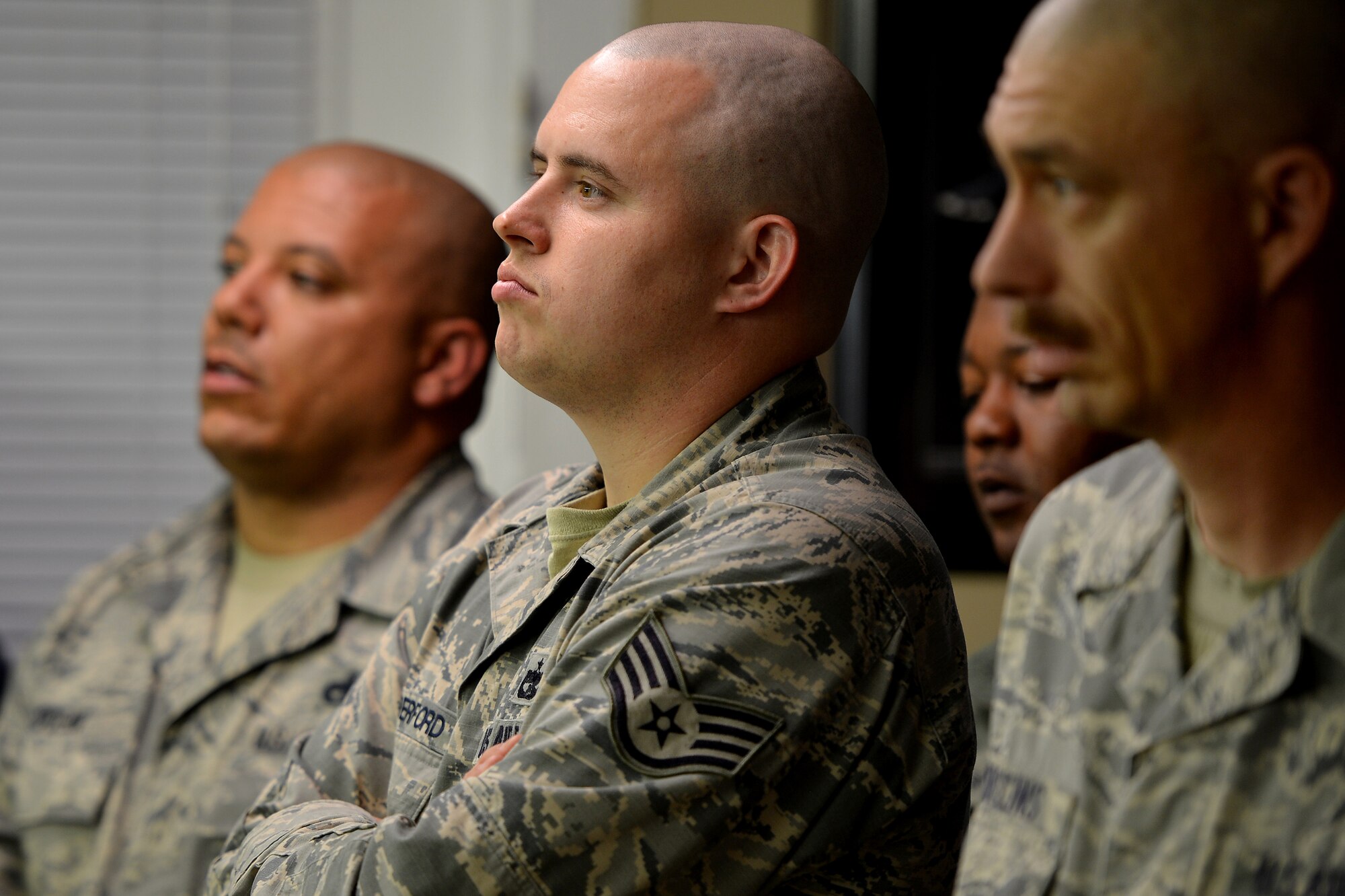 U.S. Air Force Staff Sgt. Jonathan Vanderford, 20th Logistics Readiness Squadron, (center) looks on with other coworkers from his unit while Airmen from their squadron have their heads shaved in support of a 20th LRS wingman who was recently diagnosed with cancer, March 5, 2014, Sumter, S.C. The Airmen assigned to the 20th LRS pulled together and had their heads shaved to support their wingman who is now undergoing chemotherapy. The team of Airmen expressed a “one team, one fight” mind set and plan to help their wingman as he fights cancer. (U.S. Air Force photo by Staff Sgt. Kenny Holston/Released)