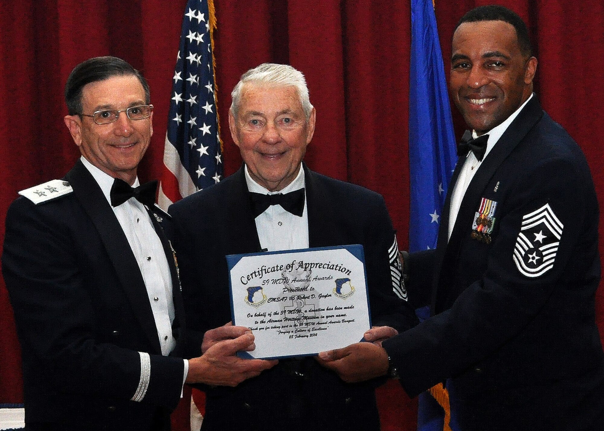 Maj. Gen. Byron Hepburn, 59th Medical Wing commander and deputy director of the San Antonio Military Health System, and Chief Master Sgt. Maurice James, 59th MDW command chief, present a letter of appreciation to retired Chief Master Sgt. of the Air Force Robert D. Gaylor after he served as the keynote speaker for the wing’s annual awards banquet Feb. 28, 2014, at the Gateway Club, Joint Base San Antonio-Lackland, Texas. The banquet recognized the wing’s outstanding performers. (U.S Air Force photo/Senior Airman Lynsie Nichols)