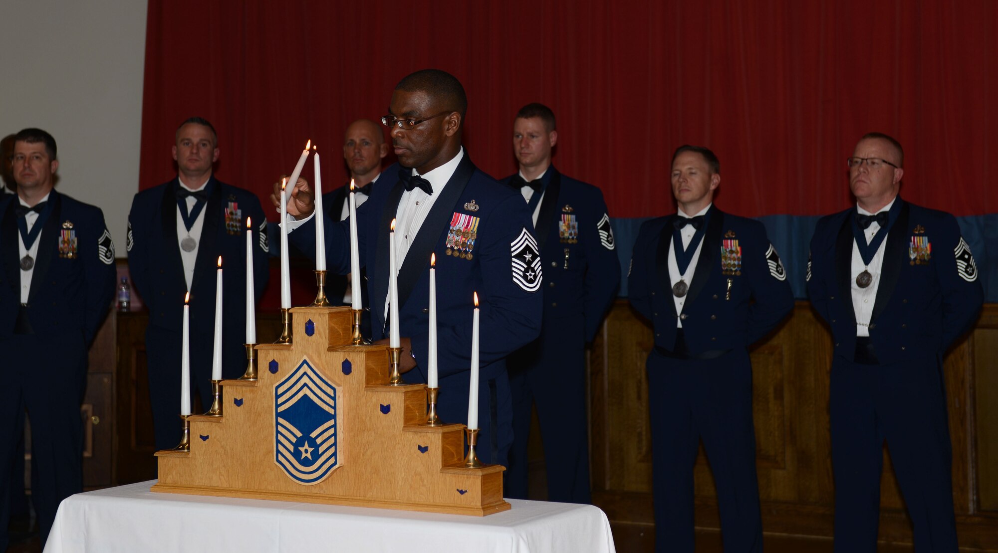 U.S. Air Force Chief Master Sgt. James E. Davis, U.S. Air Forces in Europe and Air Forces Africa command chief, lights the ninth and final candle of a candle-lighting service during the Chief Master Sergeant Recognition Ceremony March 8, 2014, on RAF Mildenhall, England. Each candle represents one enlisted rank and serves as a reminder of everything the new chief master sergeants and chief selects have accomplished during their Air Force careers. By reaching the rank of chief master sergeant, these Airmen have passed possibly the greatest milestone of their career. (U.S. Air Force photo by Airman 1st Class Preston Webb/Released)