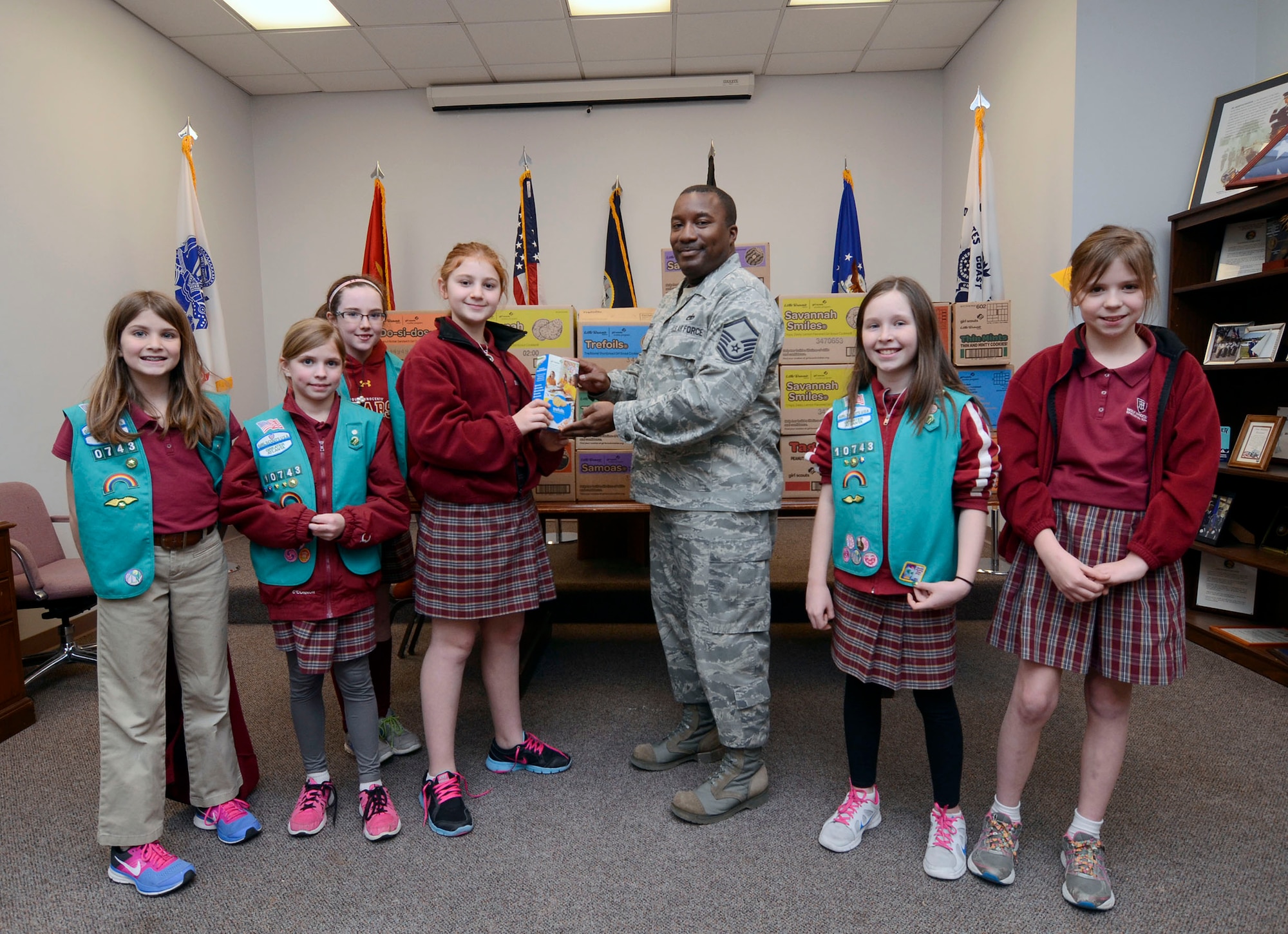 Aubrey Al-Khazraji of Girl Scout Troop 10743 presents Girl Scout cookies to Master Sgt. Aaron Albright, 94th Airlift Wing Honor Guard superintindent  Feb. 26 at the base honor guard facility. Al-Khazraji was this year's top seller, having 89 boxes donated to military personnel. Troop 10743 donated 30 cases of cookies to wing first responders. Rather than delivering the cookies via the Girl Scout Council, the members elected to deliver them personally. (U.S. Air Force photo/Don Peek)
