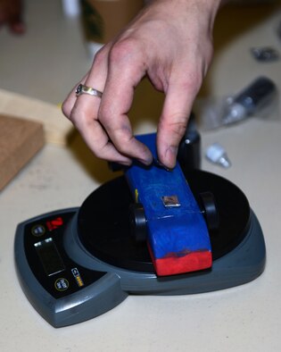 A pinewood derby car receives additional weight before the Mayflower Pinewood Derby March 8, 2014, on RAF Mildenhall, England. Cub Scouts made the cars and Scoutmasters added lead weights prior to starting the event to ensure each car weighed close to, but not more than, 5 ounces. Checking each car’s weight ensures no Cub has an unfair advantage in the competition, which focuses on design and construction as well as speed. (U.S. Air Force photo by Airman 1st Class Preston Webb/Released)