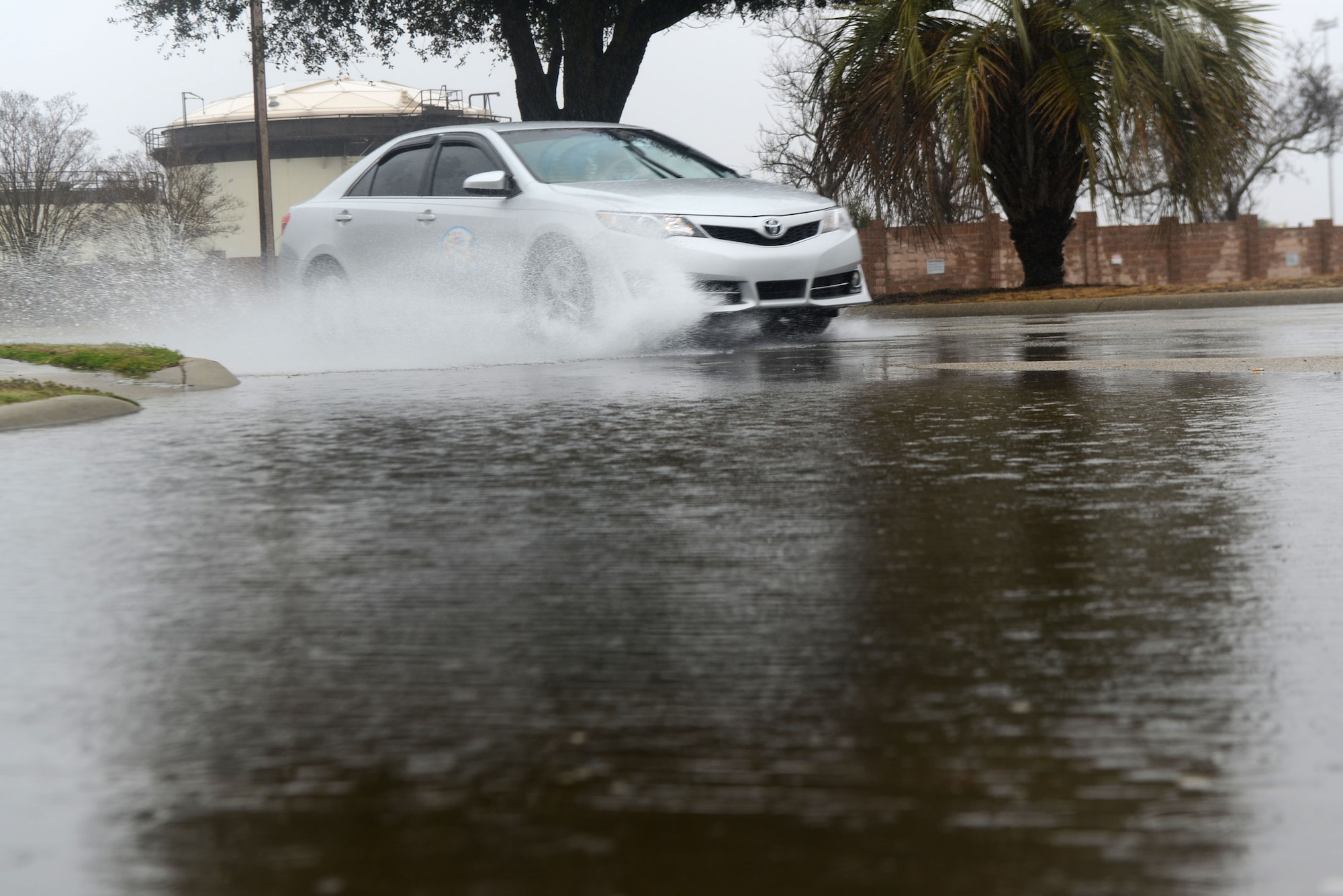 A vehicle drives through a pool of water gathered on a road at Shaw Air Force Base, S.C. March 7, 2014. Flash flooding is one of the several weather conditions that are normal for this region of the country during severe weather season which runs from March through August. (U.S. Air Force photo by Airman 1st Class Jensen Stidham/Released)
