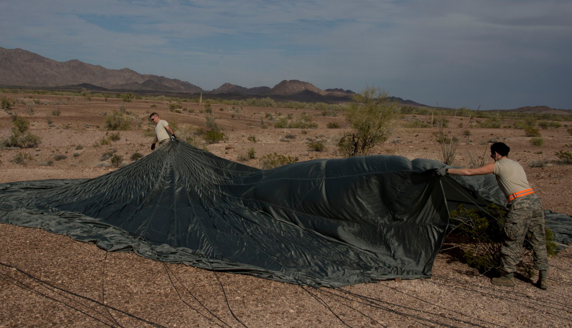 Staff Sgt. Crystal DuBois, right, and Staff Sgt. Alex Palmer, 133rd Logistic Readiness Squadron, Small Air Terminal Section, remove a parachute from the terrain in Yuma, Ariz., Feb. 25, 2014. DuBois and Palmer are two of four assigned to the recovery team. This team is responsible for recovering the training pallets released from the Minnesota Air National Guard C-130 Hercules aircraft. 
(U.S. Air National Guard photo by Tech. Sgt. Amy M. Lovgren/Released)