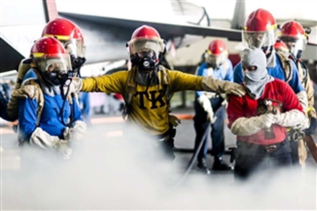 U.S. sailors fight a simulated fire during a drill in the hangar bay of the aircraft carrier USS Harry S. Truman in the Gulf of Oman, March 8, 2014. The Truman is deployed to the U.S. 5th Fleet area of responsibility, conducting maritime security operations to support theater security cooperation efforts and Operation Enduring Freedom.