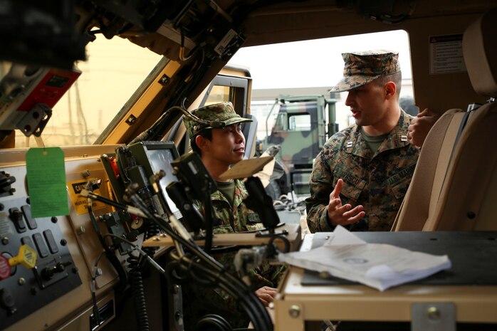 Capt. George Ivascu, motor transport company commander with Marine Wing Support Squadron 171, talks to Capt. Yushi Nakamura, officer in charge of the English program with the Japan Ground Self-Defense Force, while looking through a Mine-Resistant Ambush Protected All-Terrain vehicle, Feb. 27, 2014, during an English clinic aboard Marine Corps Air Station Iwakuni, Japan. The English clinic is an annual event hosted by the station Public Affairs Office as part of a weeklong English seminar held for members of the JGSDF.
