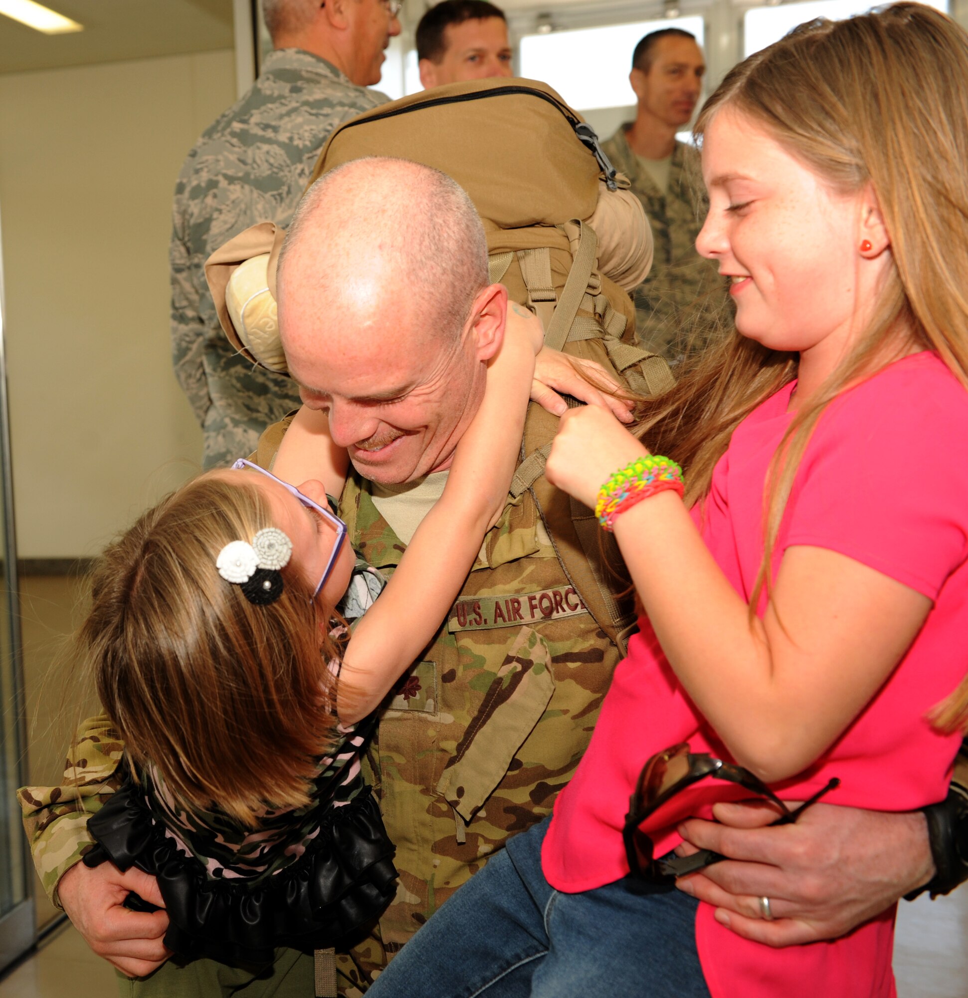 U.S. Air Force Maj. Charles Bris-bois, 31st Rescue Squadron commander, embraces his daughters, Miki and Carolina, during redeployment at the 733rd Air Mobility Squadron Passenger Terminal on Kadena Air Base, Japan, March 10, 2014. Twenty-seven service members assigned to the 18th Operations Group returned to home station after being deployed and were greeted by family, friends and coworkers upon arrival. (U.S. Air Force photo by Airman 1st Class Hailey R. Staker)