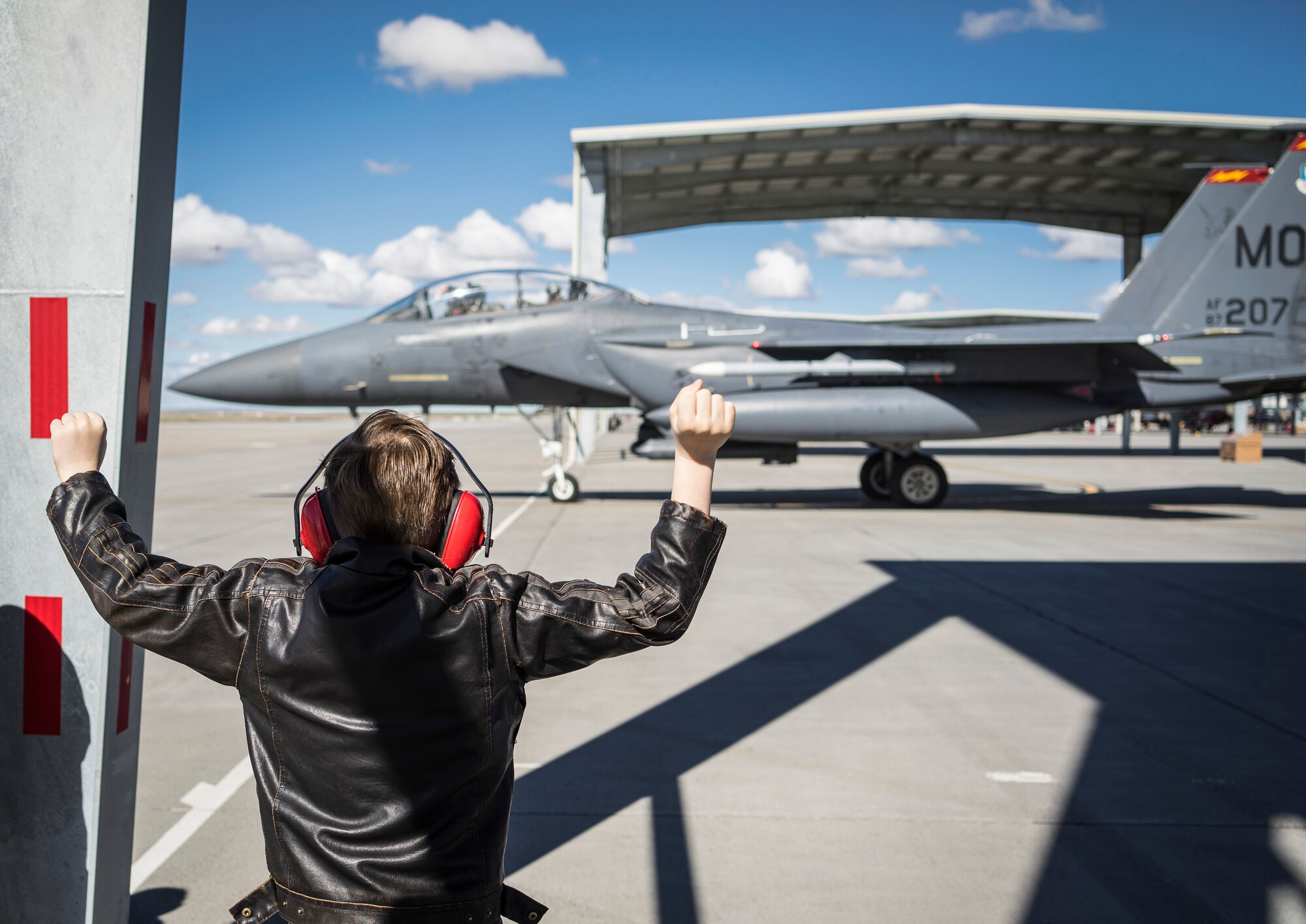 William Ciluaga, also known as "Idaho William," cheers-on an F-15E Strike Eagle at Mountain Home Air Force Base, Idaho, March 7, 2014. Ciluaga runs a YouTube channel with his mother, creating videos about the history and culture of prominent Idaho location, traveling more than 3,000 miles in the past year. (U.S. Air Force photo by Tech. Sgt. Samuel Morse/RELEASED)