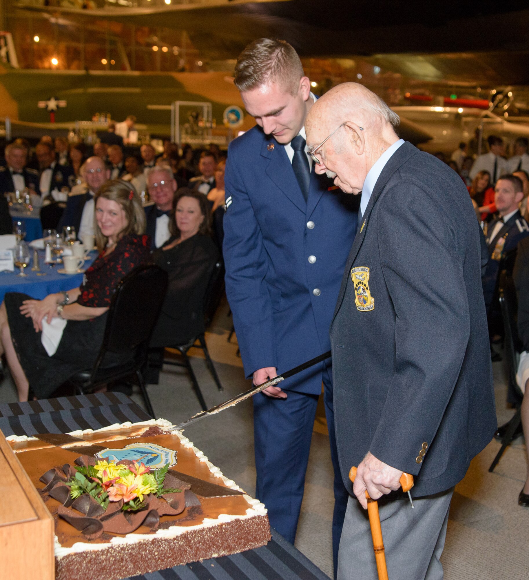 Airman 1st Class Jason Siegfried, 446th Aircraft Maintenance Squadron, assists Lt. Col. (Ret.) Ed Saylor, Doolittle Raider, in cutting the cake at the 446th Airlift Wing Awards Banquet March 8 at Boeing’s Museum of Flight in Seattle.  Saylor, one of 80 Airmen of the U.S. Army Air Corps, led by Lieutenant Colonel Jimmy Doolittle, carried the battle of the Pacific to the heart of the Japanese empire with a surprising and daring raid on military targets. He served for the remainder of World War II and after the war, retiring as an aircraft maintenance officer.  (Courtesy photo by David Lobban, Lobban Photography Inc.)