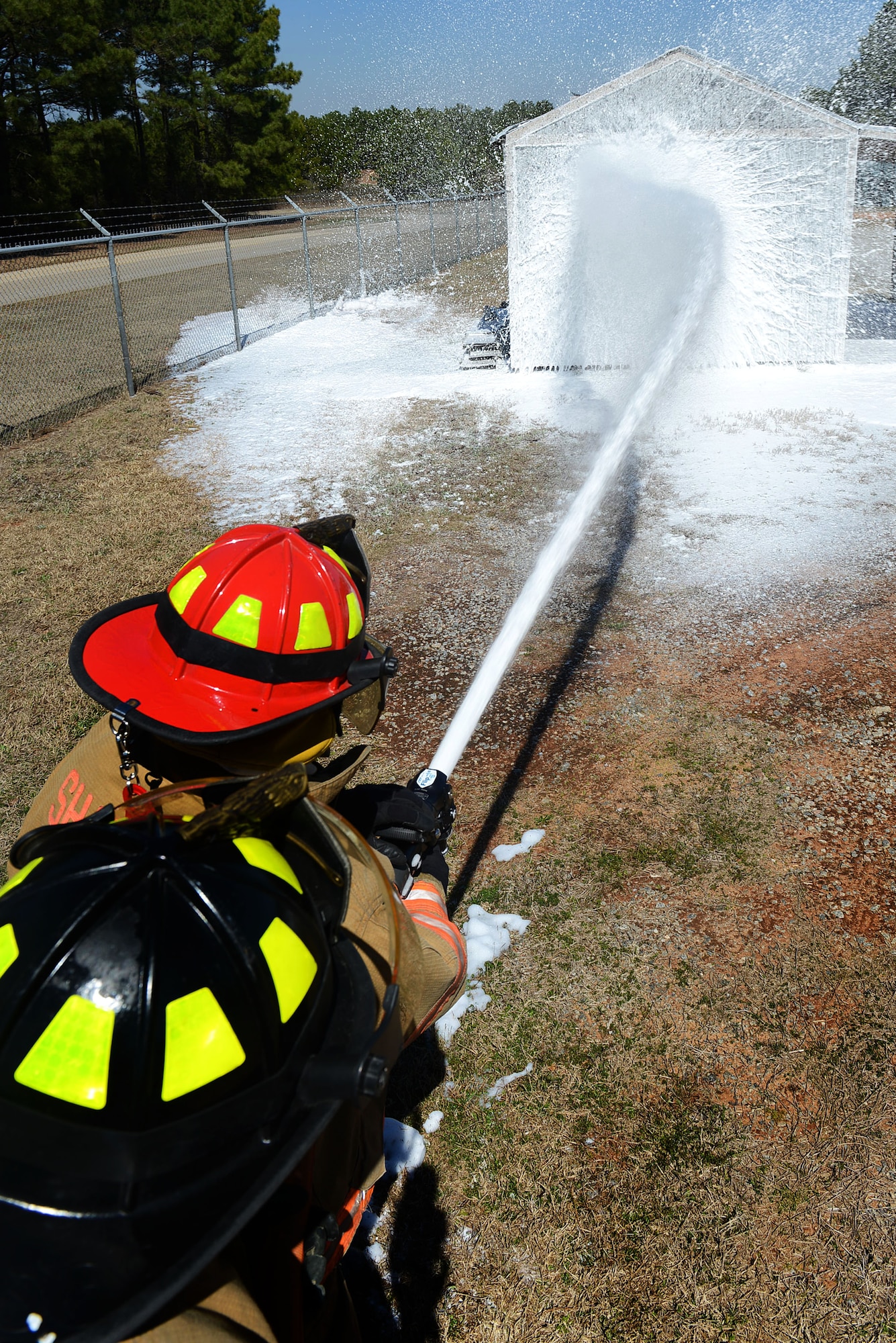 U.S. Air Force Staff Sgt. Patrick Bentley and Senior Airman Wesley Martin, 20th Civil Engineer Squadron firefighters, train with compressed air foam on a fixed structure at Shaw Air Force Base, S.C., March 10, 2014. 20th CES Airmen familiarized themselves with the new CAF a mixture of foam, water and air which cools the temperature of a structure down while also distinguishing flames. (U.S. Air Force photo by Airman 1st Class Jensen Stidham/Released)