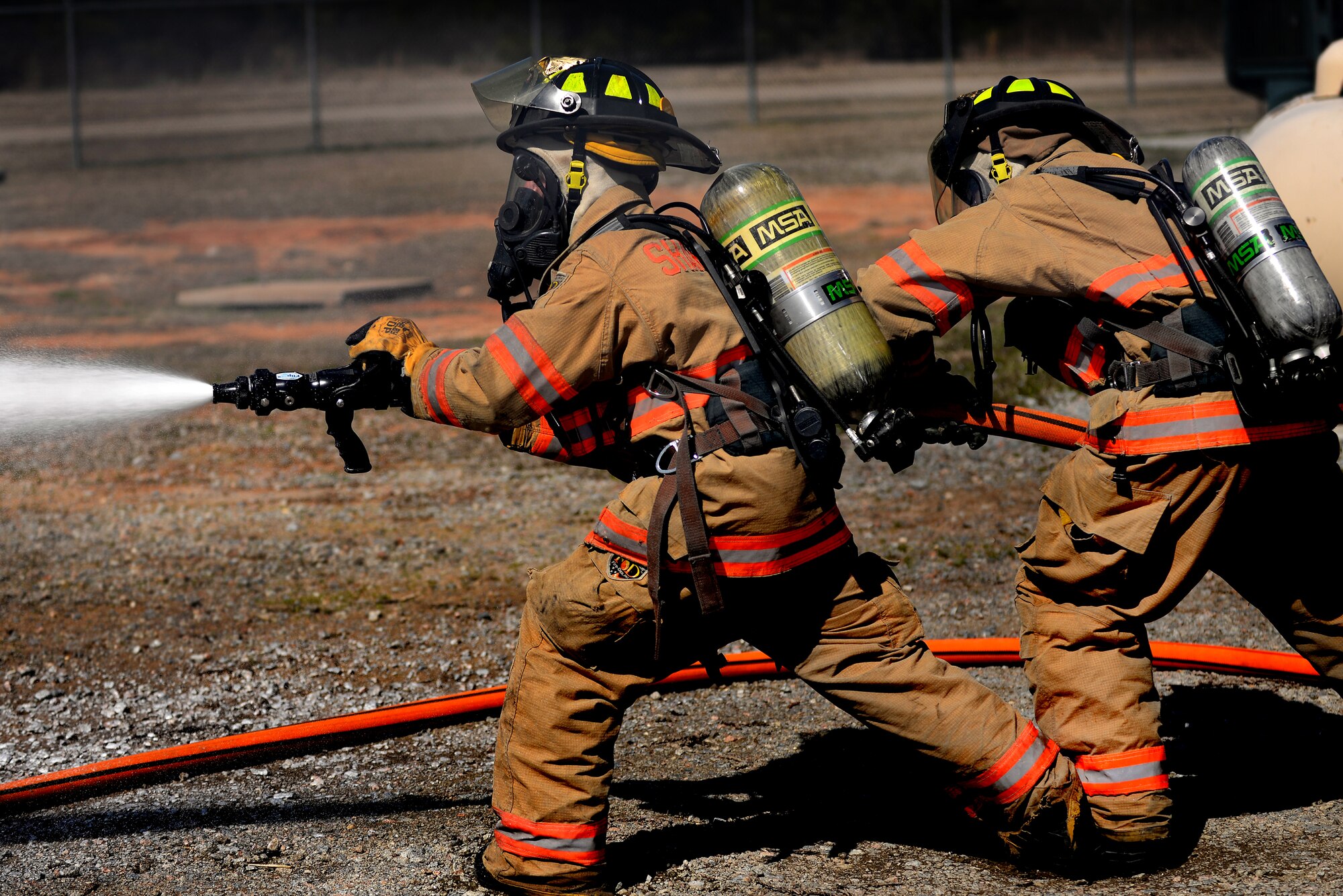 U.S. Air Force Senior Airmen Brandon Young and Wesley Martin, 20th Civil Engineer Squadron firefighters, extinguish a controlled car fire with the new compressed air foam system, Shaw Air Force Base, S.C. March 10, 2014. The new CAF system is a way to cool down a structure on fire by emitting millions of bubbles that trap British thermal units, the amount of heat required to raise the temperature of one pound of water. (U.S. Air Force photo by Airman 1st Class Michael A. Cossaboom/Released)