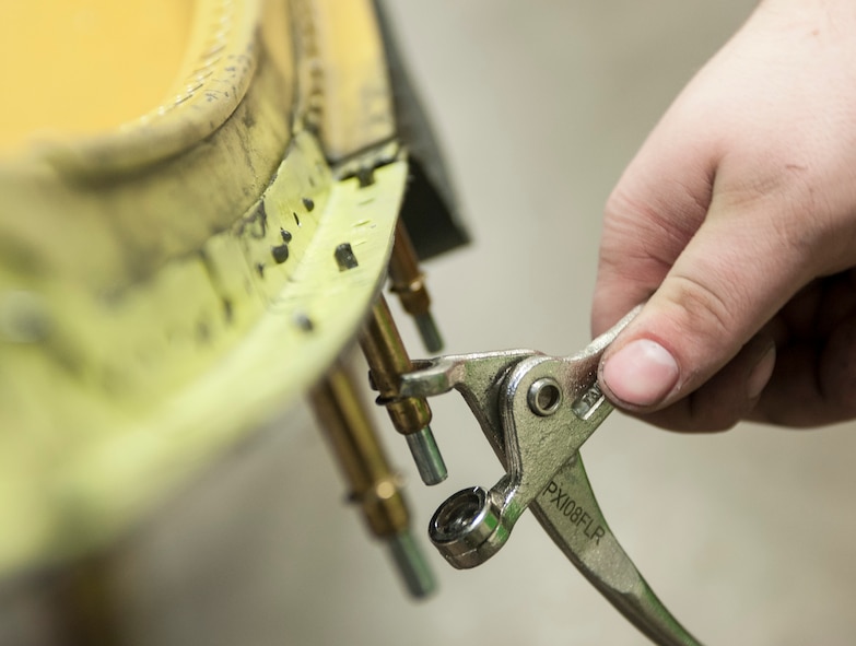 A hand tool is used to secure rivets to part of a -52H Stratofortress in the sheet metal shop at Minot Air Force Base, N.D., March 6, 2014. The shop utilizes a wide range of tools to complete repairs including simple hand tools, air powered drills and pneumatic rivet squeezers. (U.S. Air Force photo/Senior Airman Stephanie Sauberan)