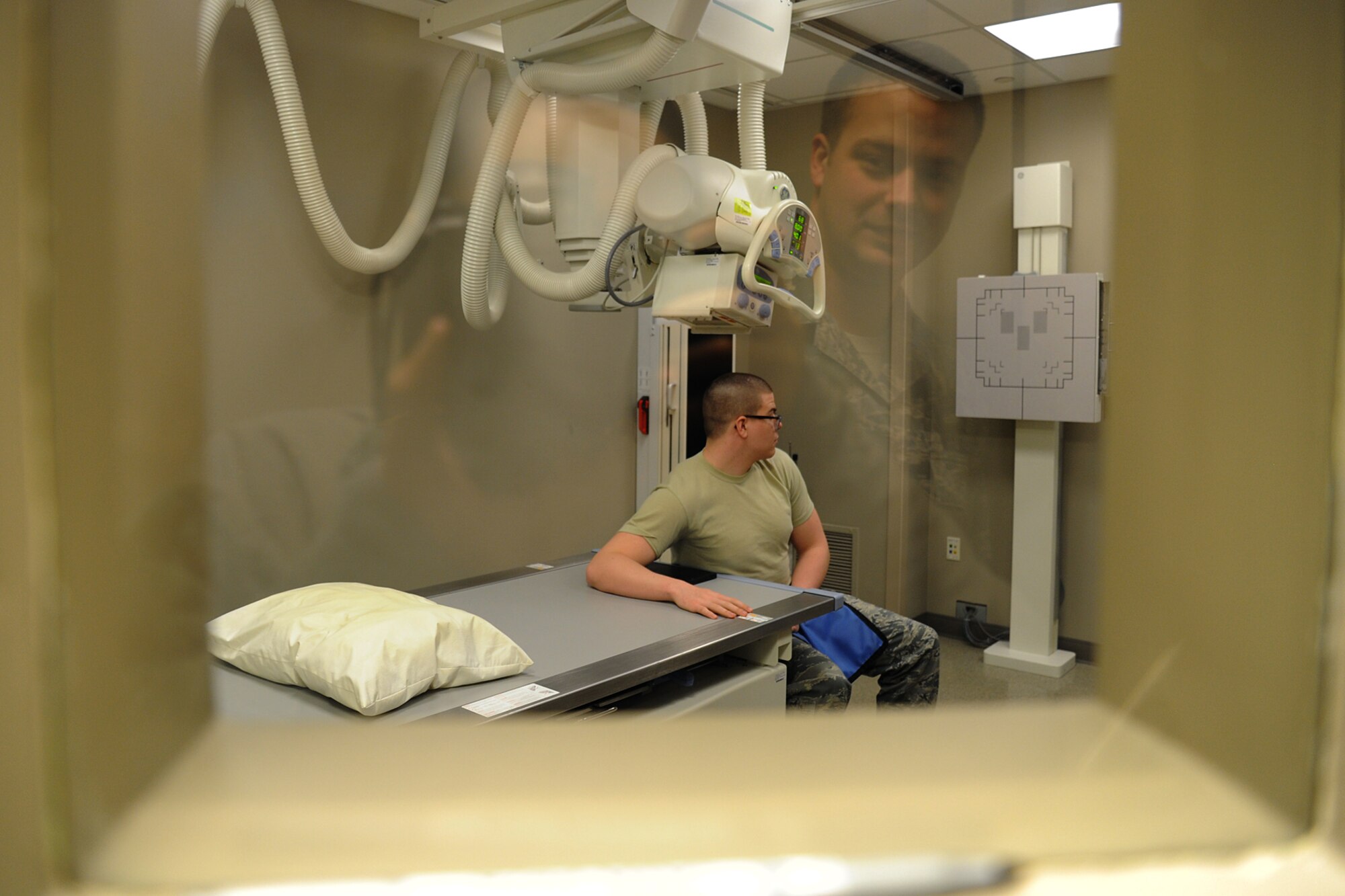 Senior Airman Timothy Carlson, 92nd Medical Support Squadron radiology technologist, shoots an x-ray behind lead lined walls at Fairchild Air Force Base, Wash., March 10, 2014. The Diagnostic Imaging Flight provides medical support for both the 92nd and 141st Air Refueling Wings and tenant units at Fairchild. (U.S. Air Force photo by Airman 1st Class Janelle Patiño/Released)