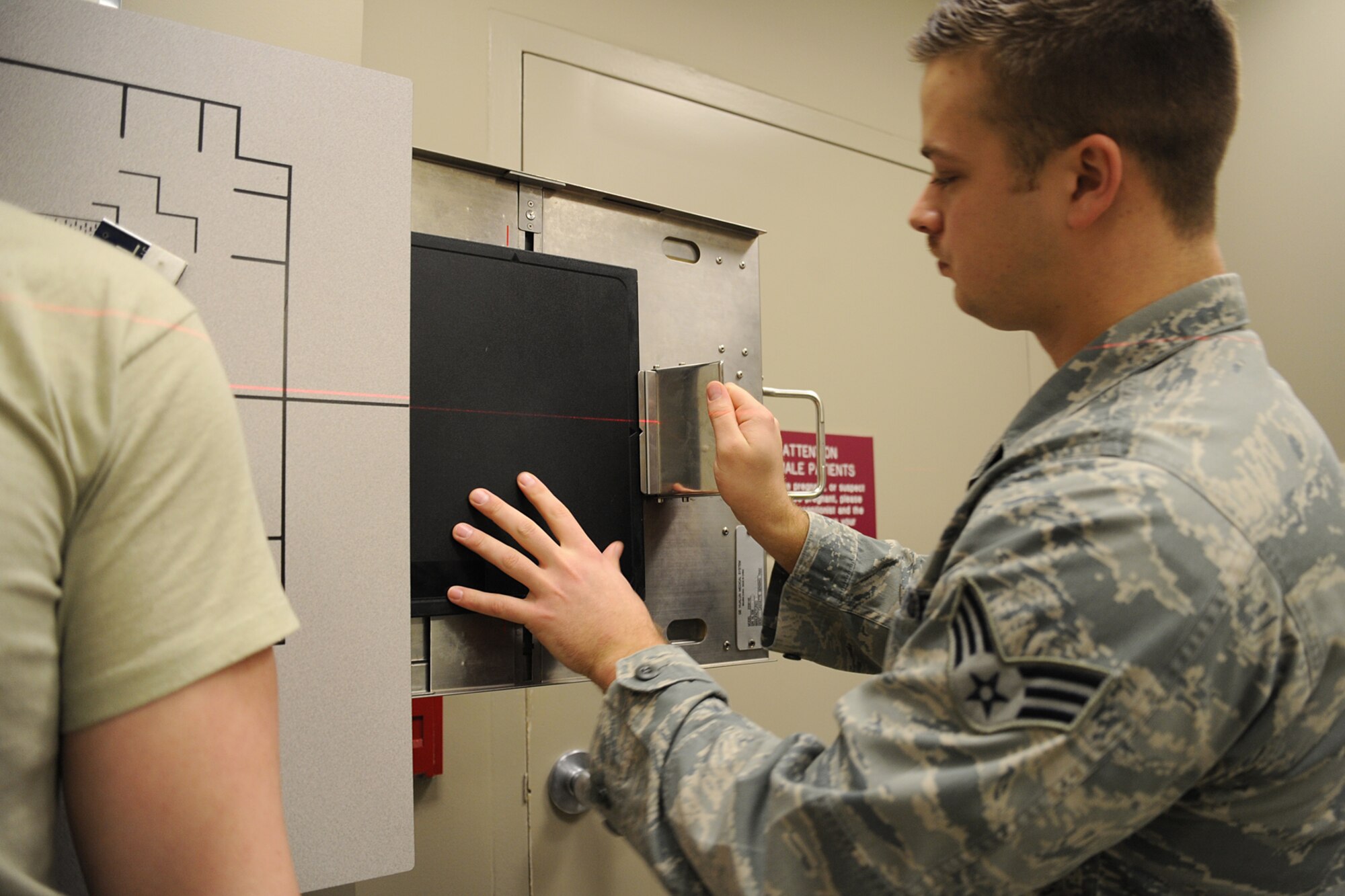 Senior Airman Timothy Carlson, 92nd Medical Support Squadron radiology technologist, inserts an imaging plate into the image receptor to conduct an x-ray at Fairchild Air Force Base, Wash., March 10, 2014. The Diagnostic Imaging Flight provides medical support for both the 92nd and 141st Air Refueling Wings and tenant units. (U.S. Air Force photo by Airman 1st Class Janelle Patiño/Released)