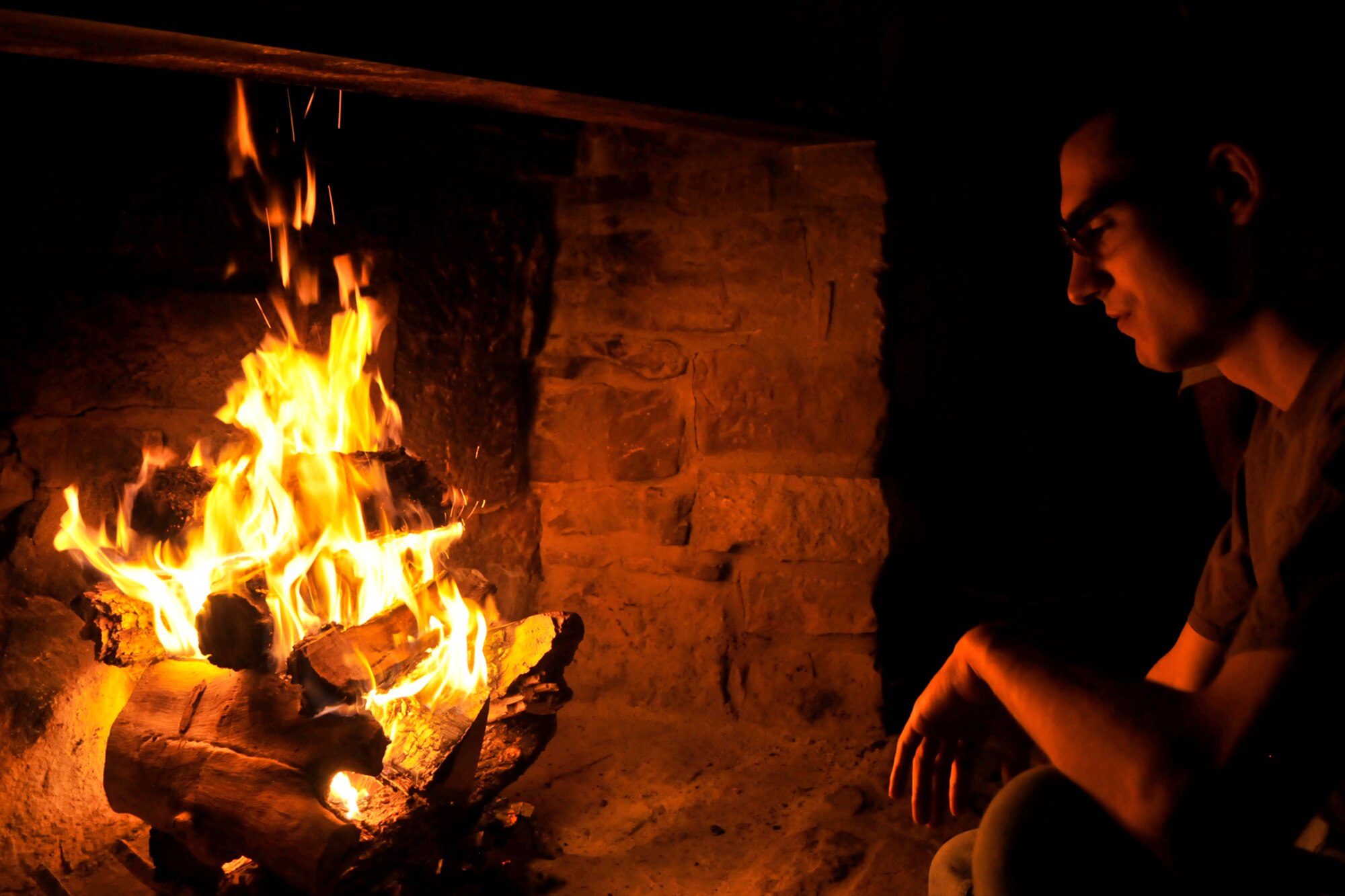 SAN ANGELO, Texas – Airman 1st Class Lewis Moore, 17th Training Wing Knowledge Operations management technician, sits by a fireplace during the Overnight Excursion at Fort Concho Feb. 28. The fire was the only thing keeping the barracks warm and the heat from the fire traveled through metal vents that hung from the ceiling of the barracks. (U.S. Air Force photo/ Airman 1st Class Devin Boyer)
